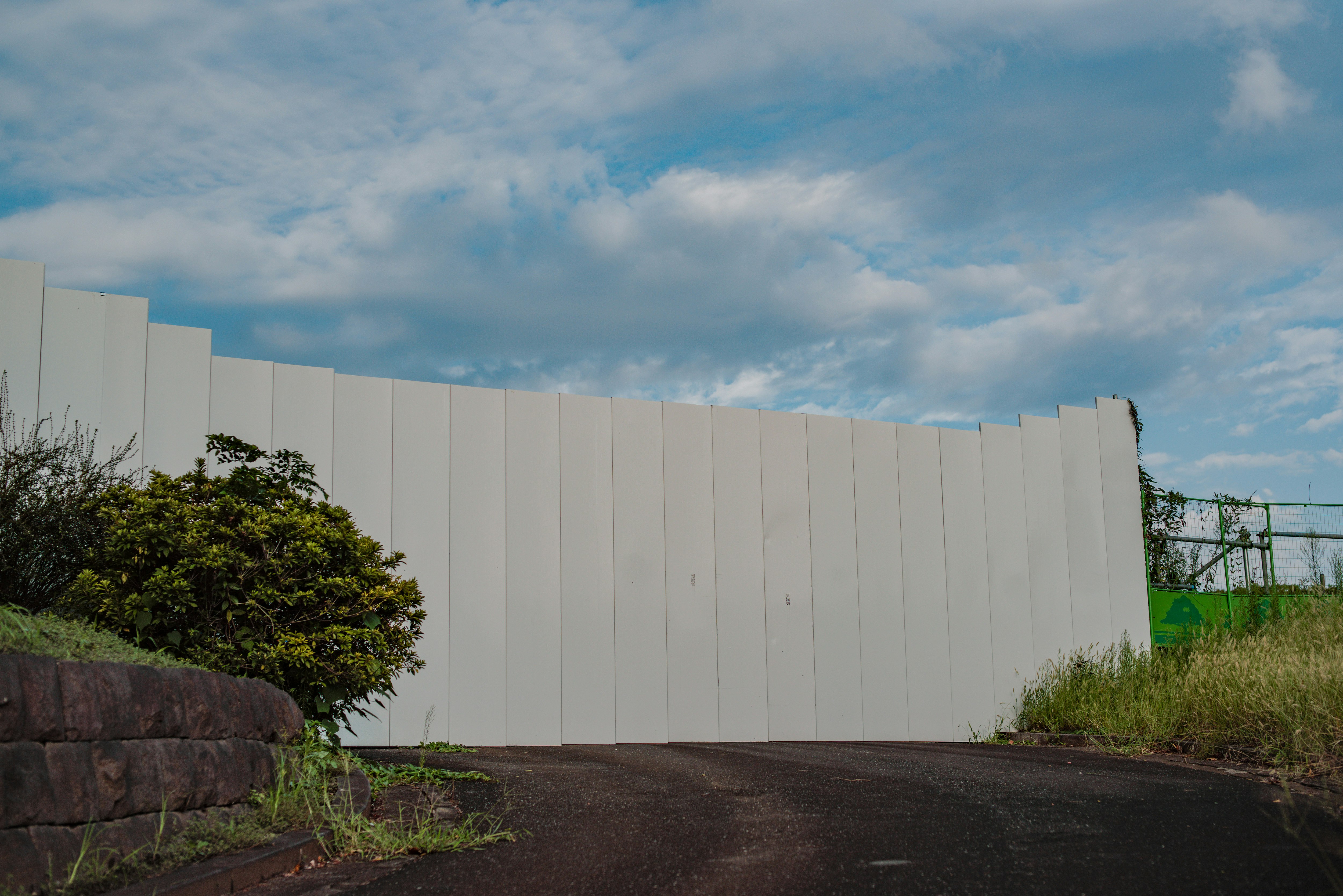 仮囲いのある行き止まりの通路と秋の空・草木の景色