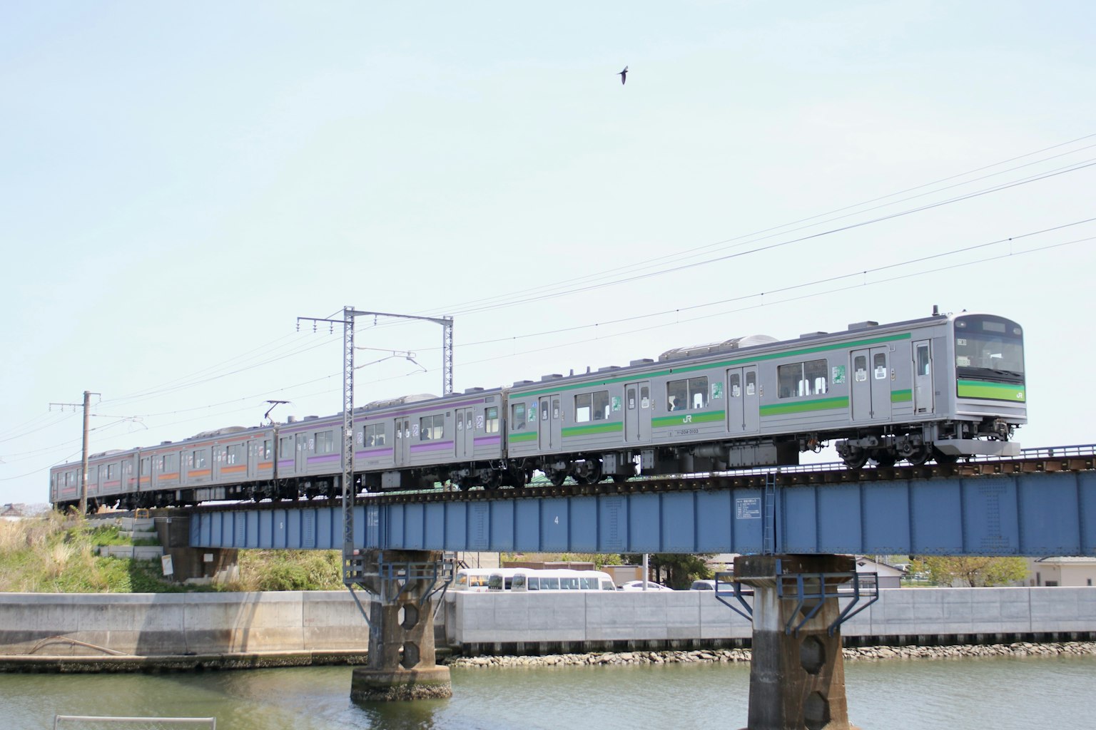 Un train avec une bande verte traversant un pont au-dessus de l'eau