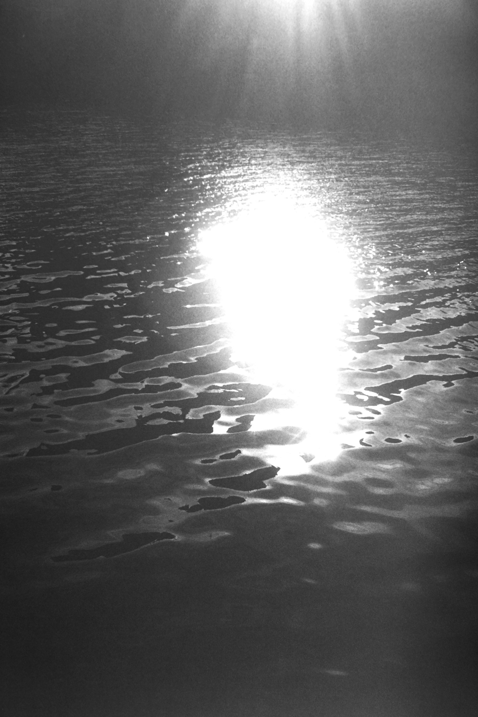 Schwarzweißbild, das den Lichtreflex auf der Wasseroberfläche zeigt