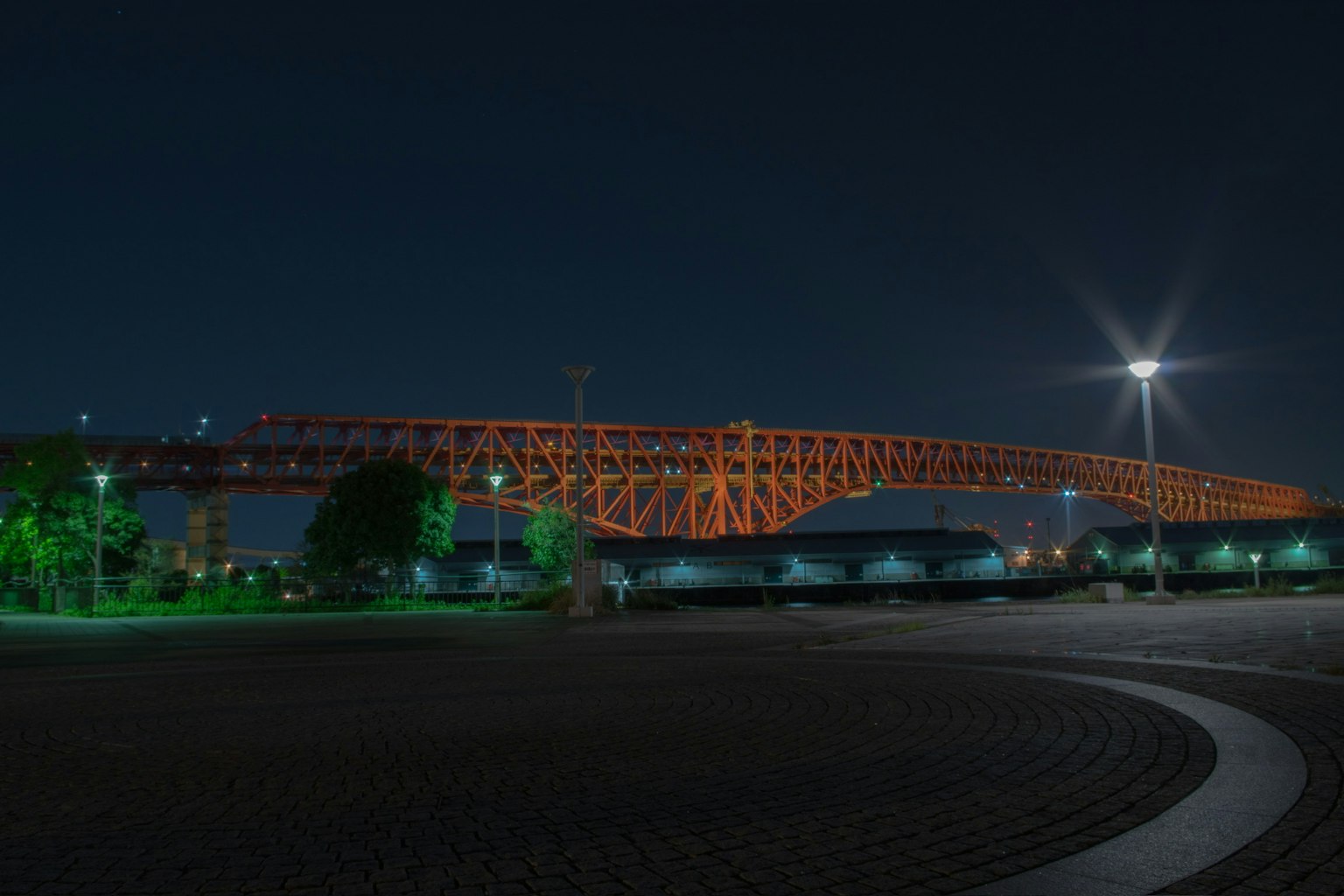 夜の公園にあるオレンジ色の橋と周囲の緑の照明