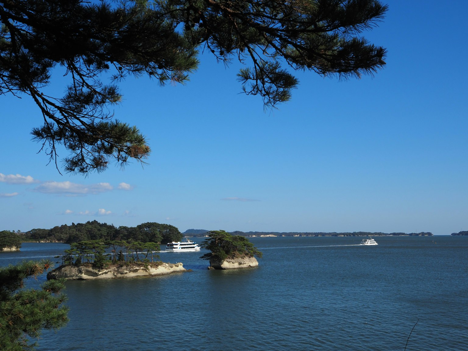 Scenic view of small islands and boats on calm water under a blue sky