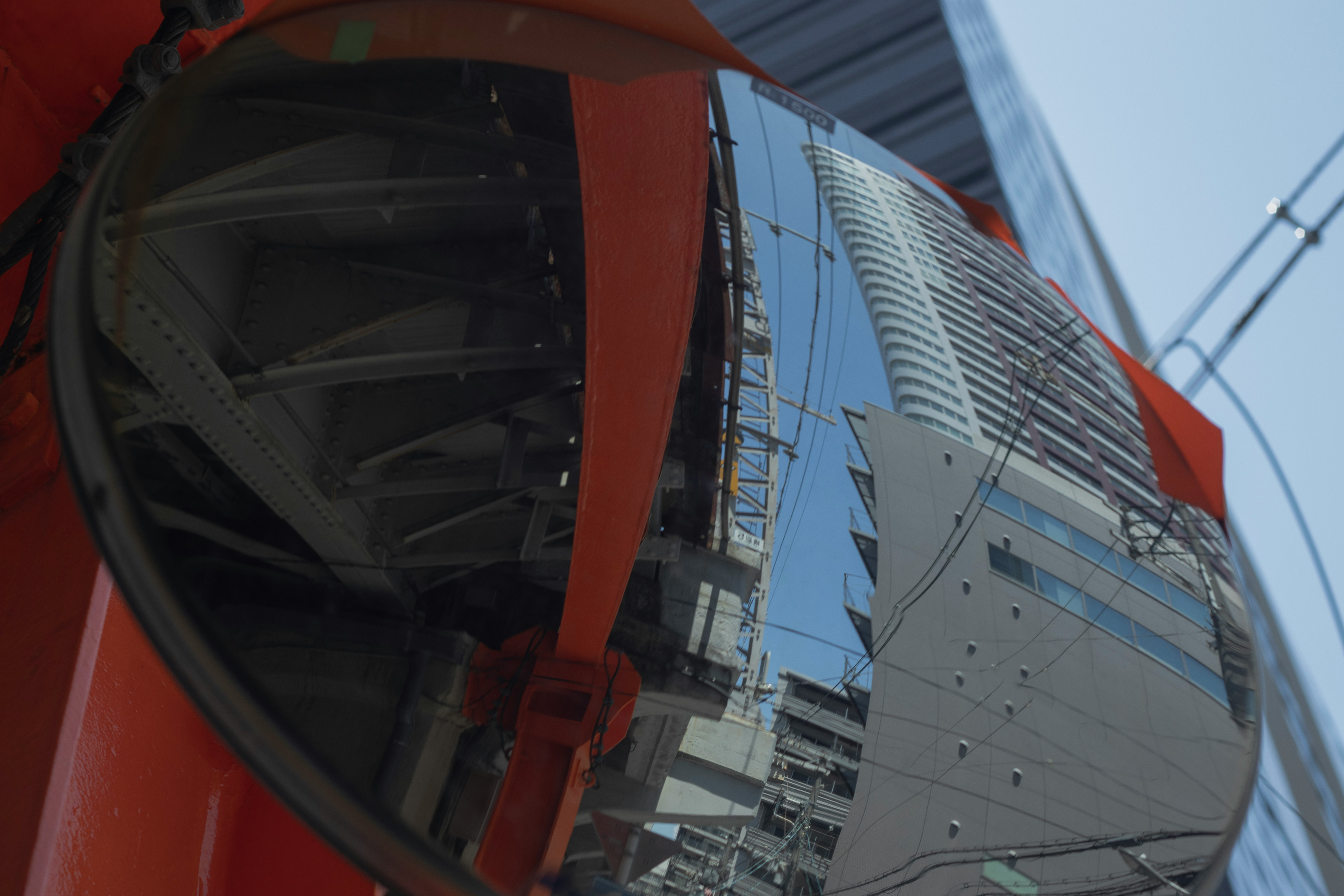 chantier vu à travers l’armature d’une grue rouge, vue vers le haut sur des immeubles