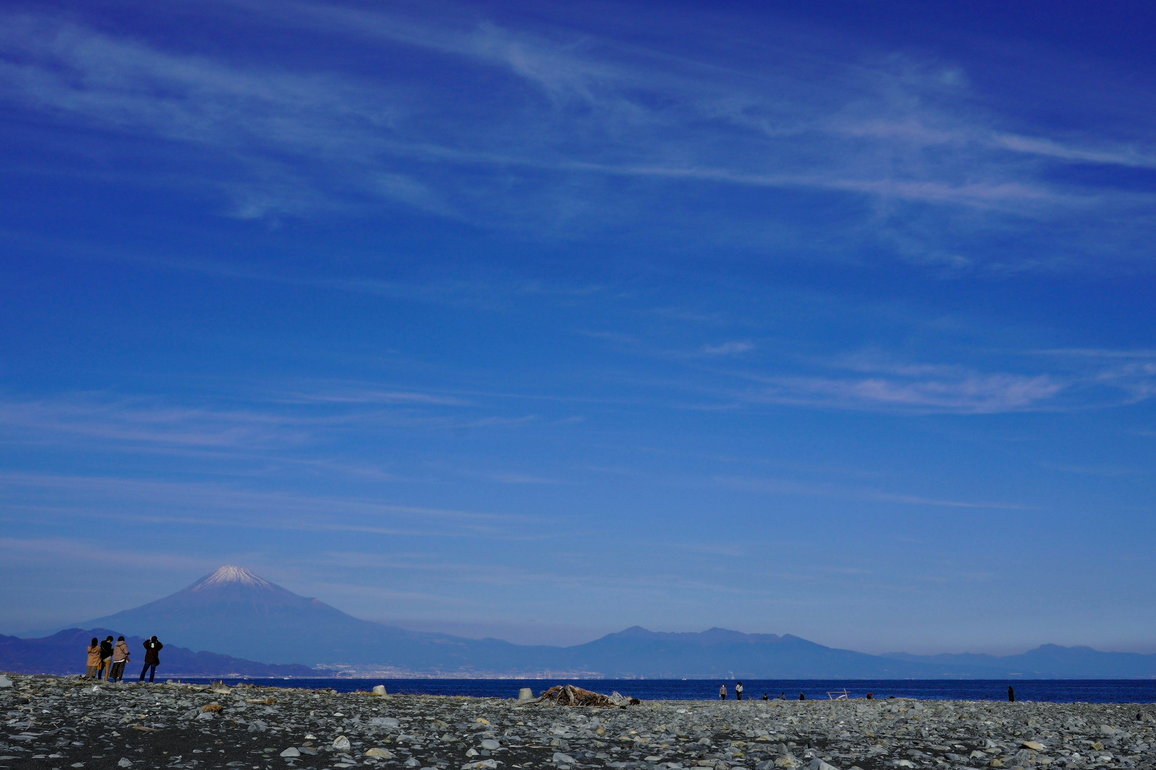 海辺の岩場と遠くの山並みが見える青空の風景