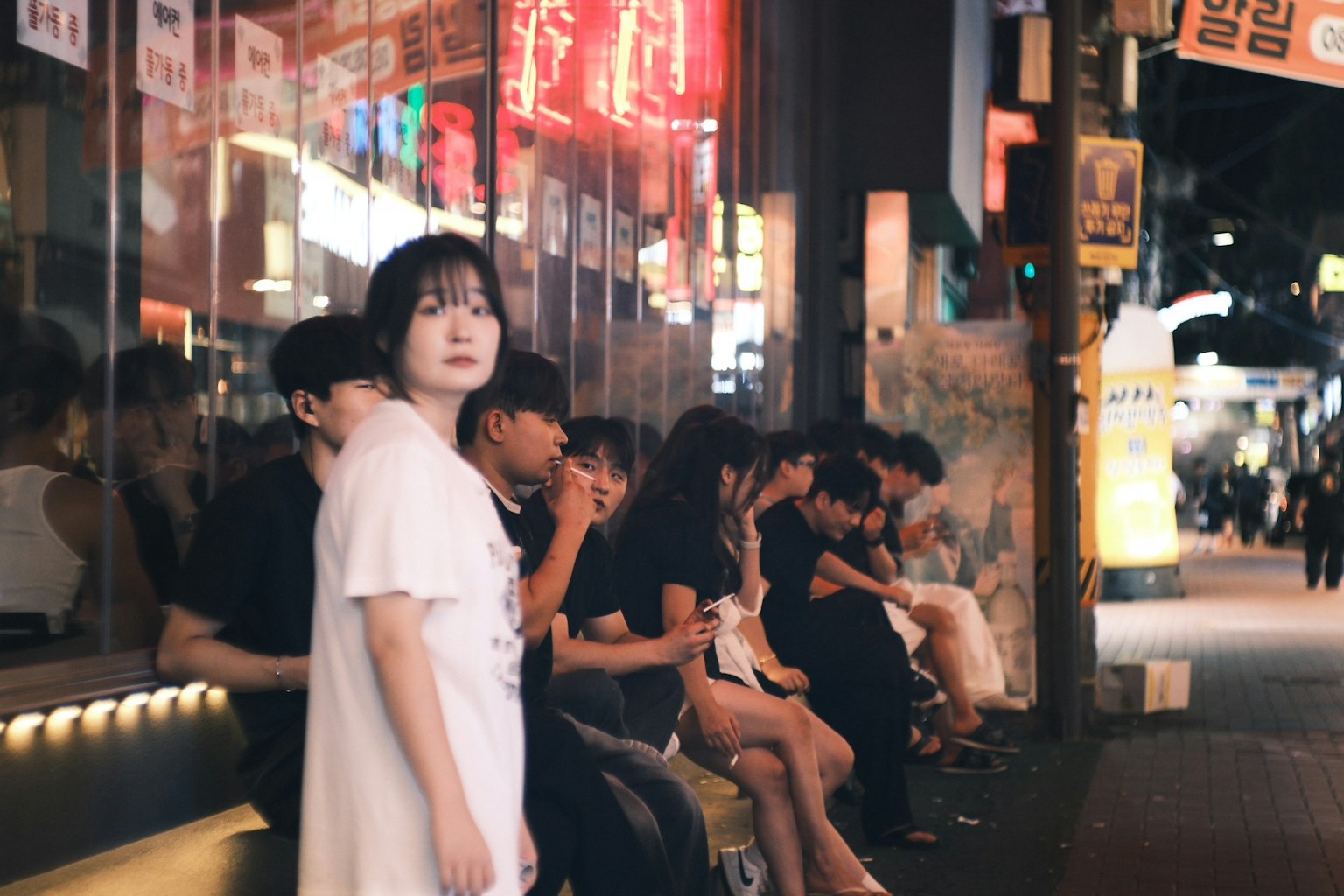 夜の街で座っている若者たちと立っている女性のグループ