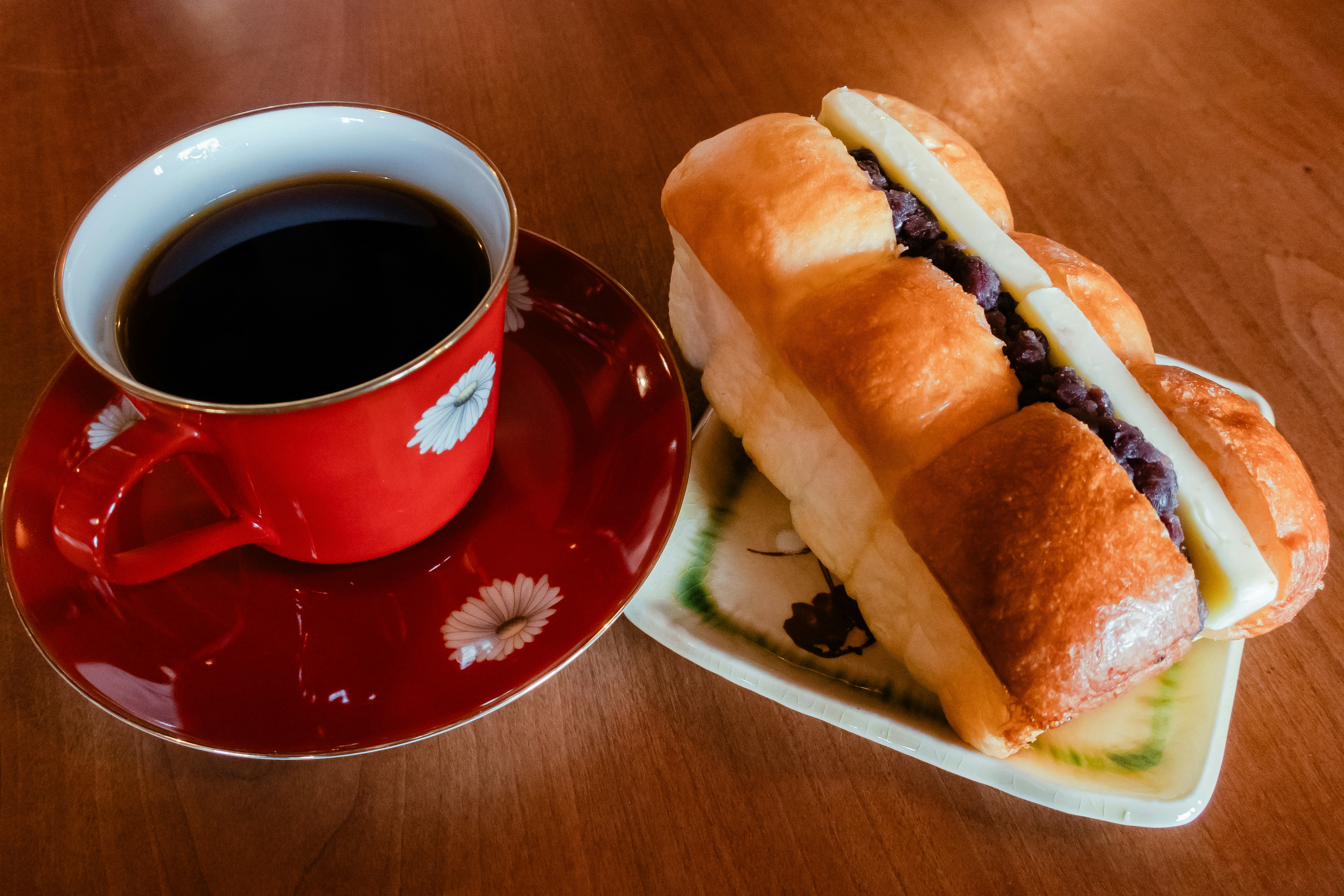 赤いカップのコーヒーとあんバターの焼きたてパン