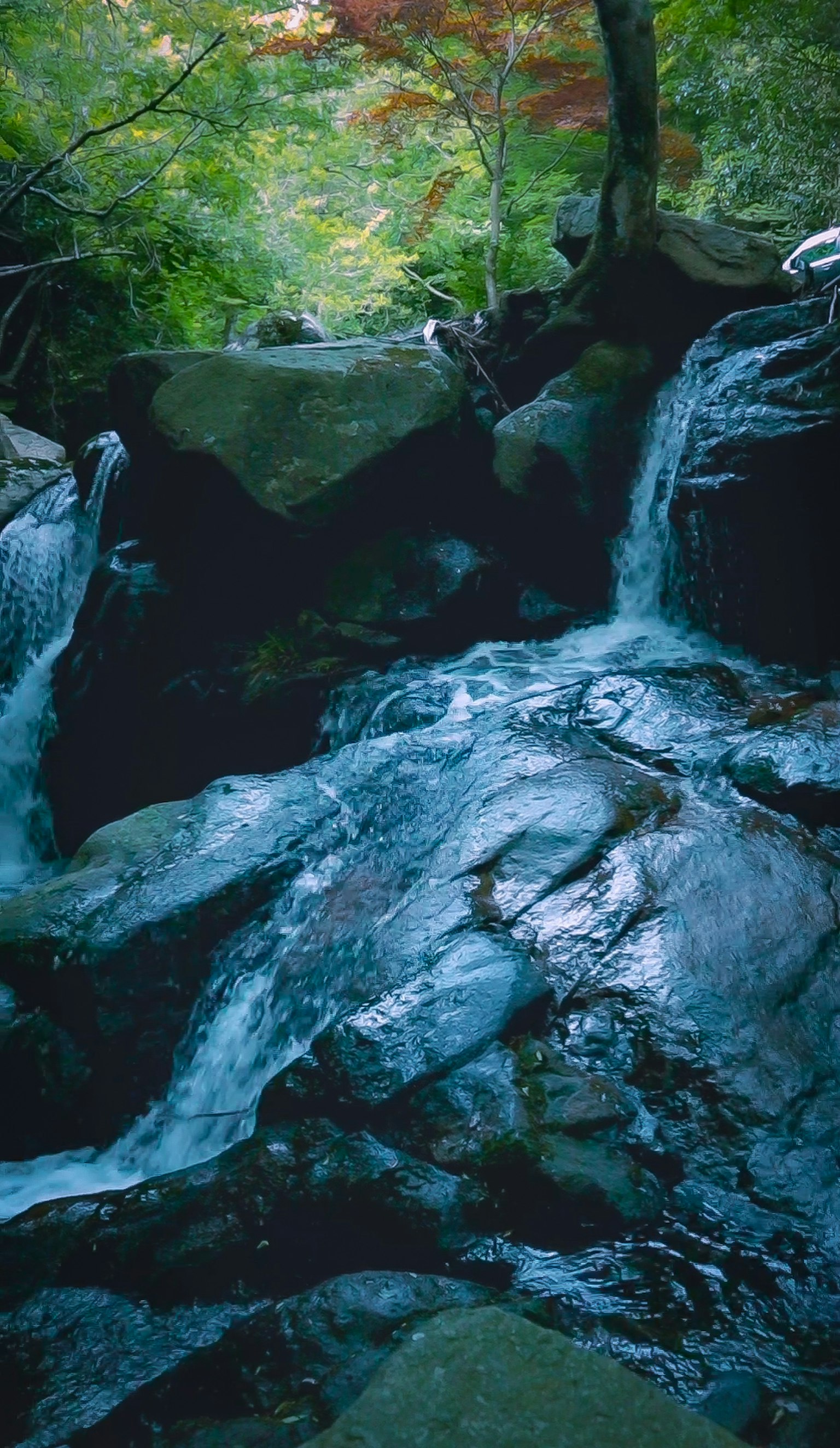 寧靜的瀑布場景，藍色水流過岩石