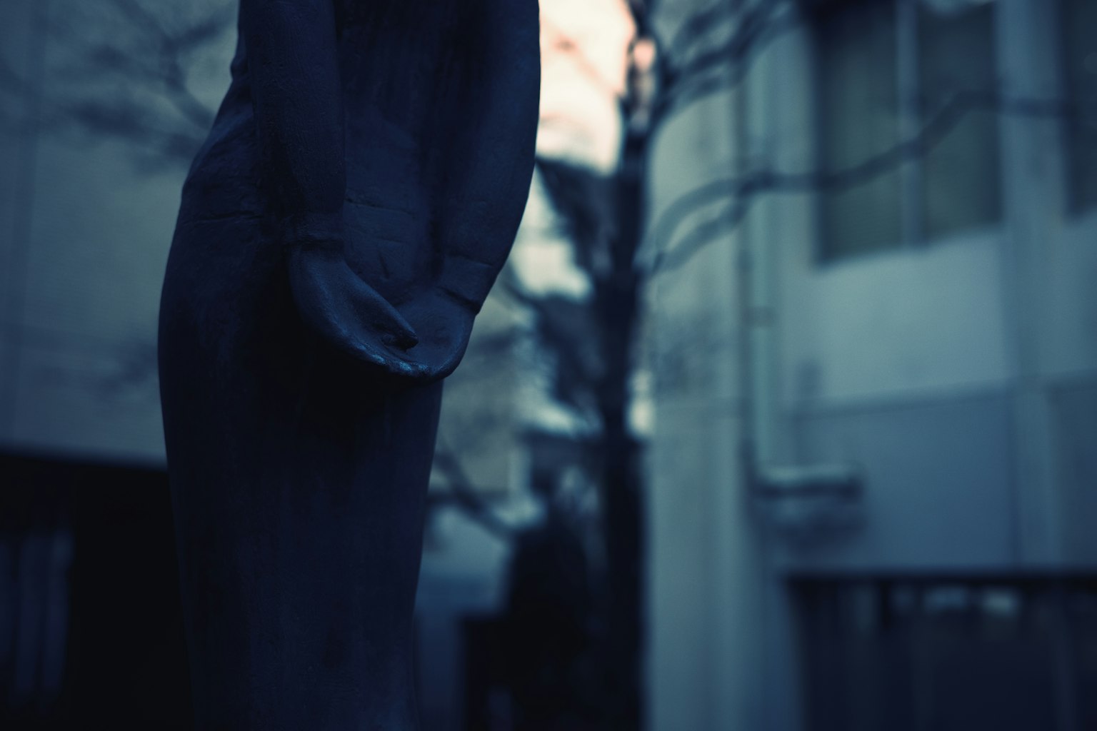 Vue latérale d'une sculpture sombre ressemblant à une figure sur un fond flou
