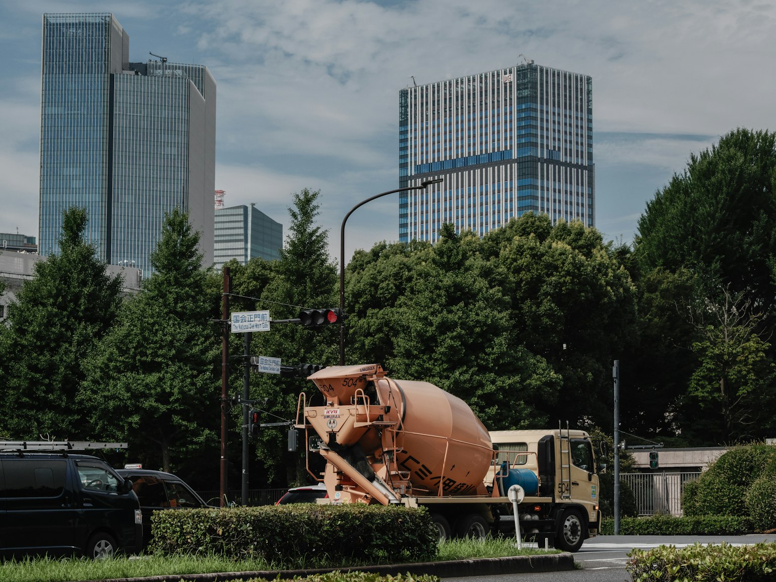 Camion per cemento che circola su una strada circondata da edifici e vegetazione