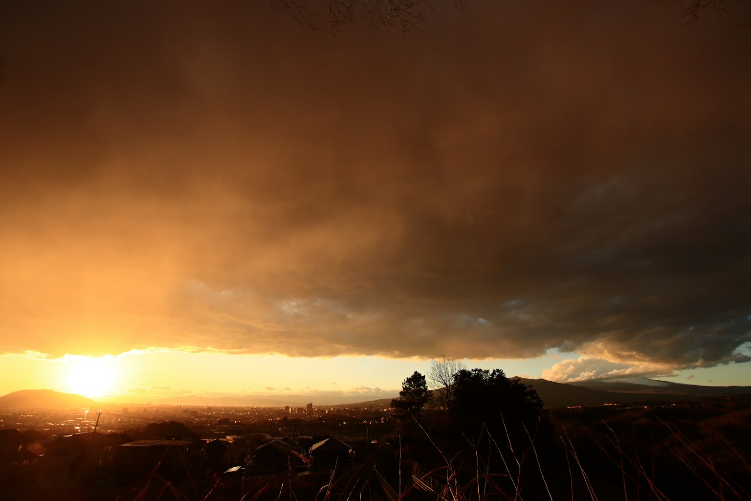 Paesaggio al tramonto con nuvole scure e tonalità arancioni vivaci