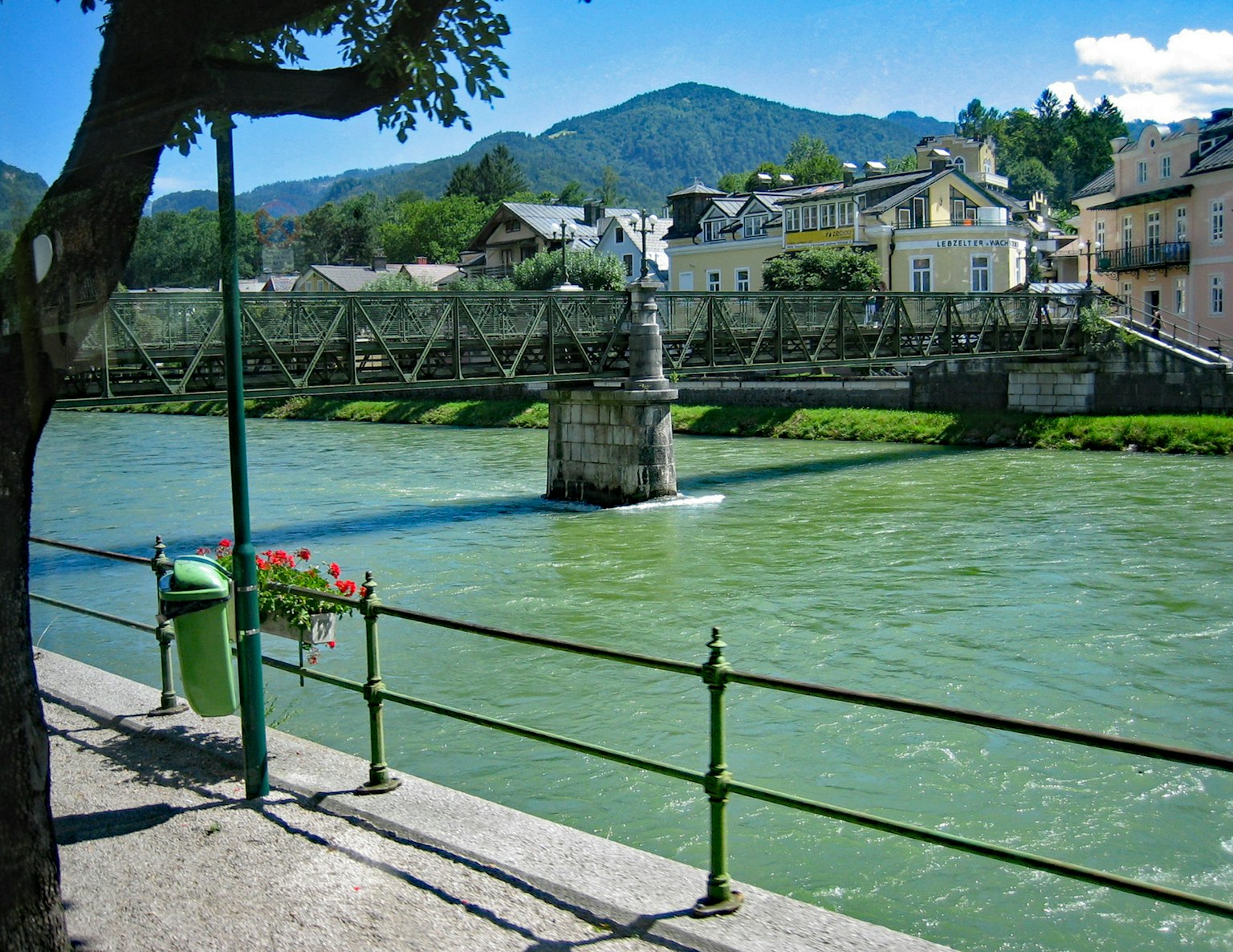 Malersicher Blick auf einen blauen Fluss mit einer Brücke bunte Gebäude und Berge