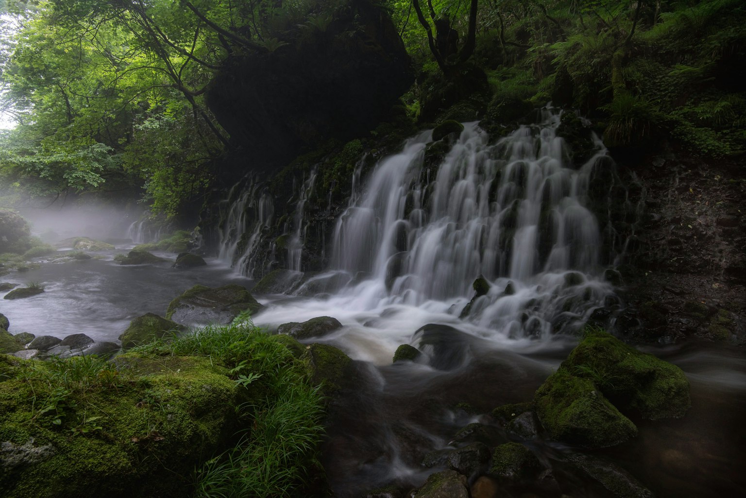 Chute d'eau sereine entourée de verdure luxuriante avec un flux d'eau et de la brume