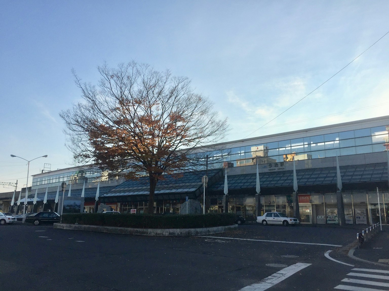 Edificio moderno con grandi finestre e un albero sotto un cielo blu