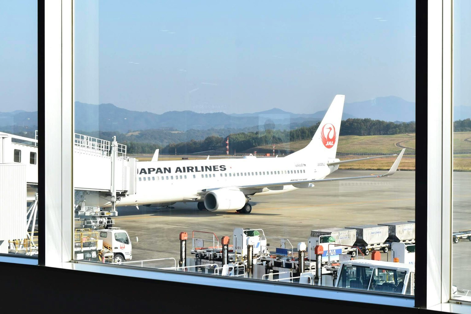 Avion Japan Airlines vu à travers une fenêtre d'aéroport
