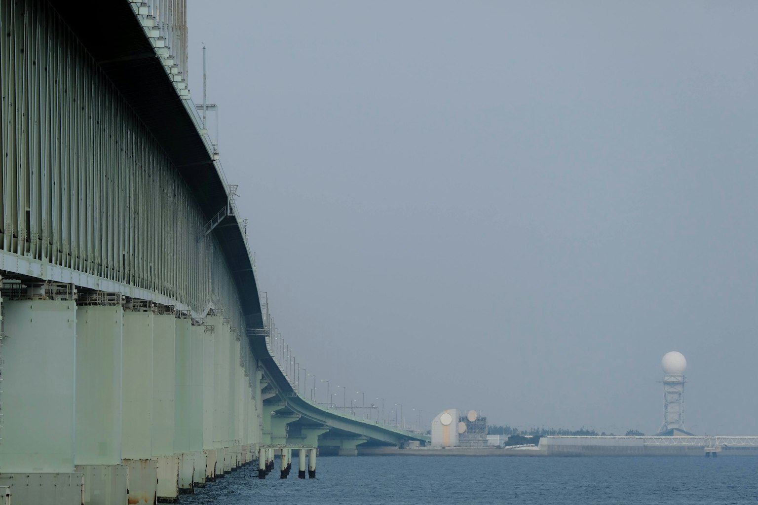 View of a bridge over calm water under a cloudy sky