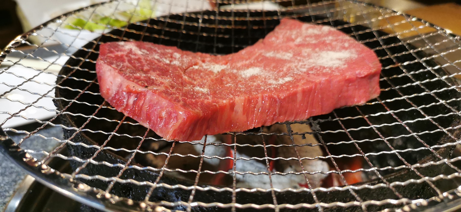 Pezzo di carne cruda su una griglia a carbone