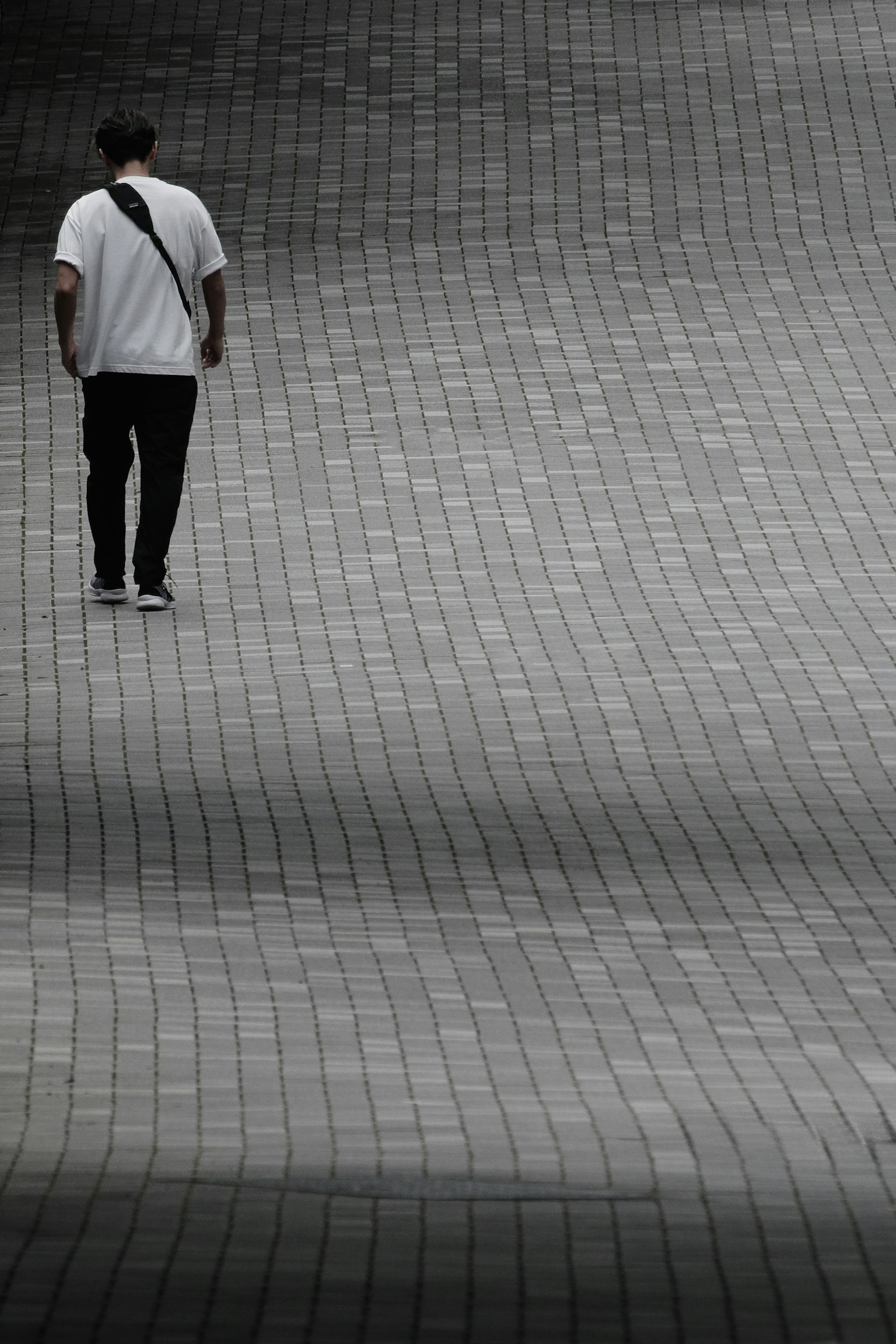 Un uomo in camicia bianca che cammina su un marciapiede ondulato