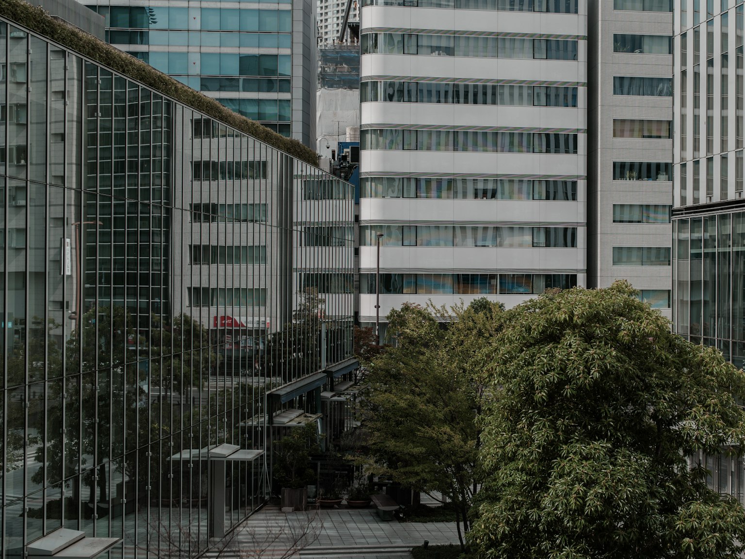 Urban landscape with high-rise buildings and green trees worker operating a crane
