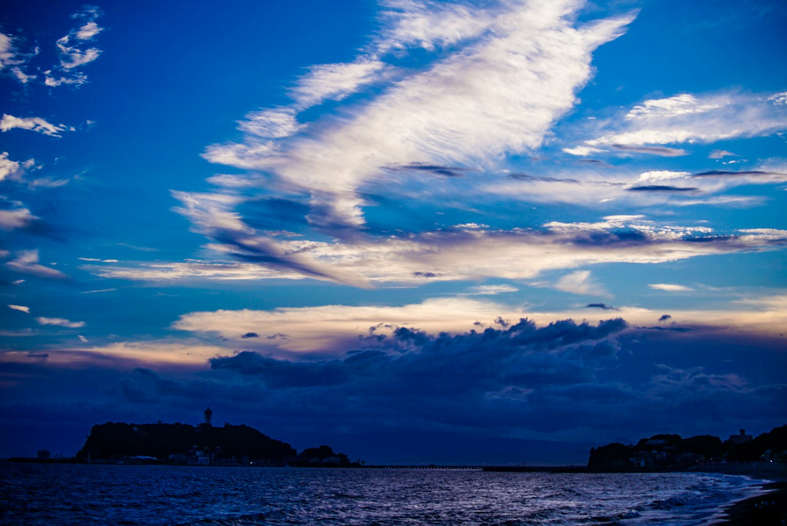 Bellissima vista del tramonto sull'oceano con nuvole basse e cielo blu in contrasto
