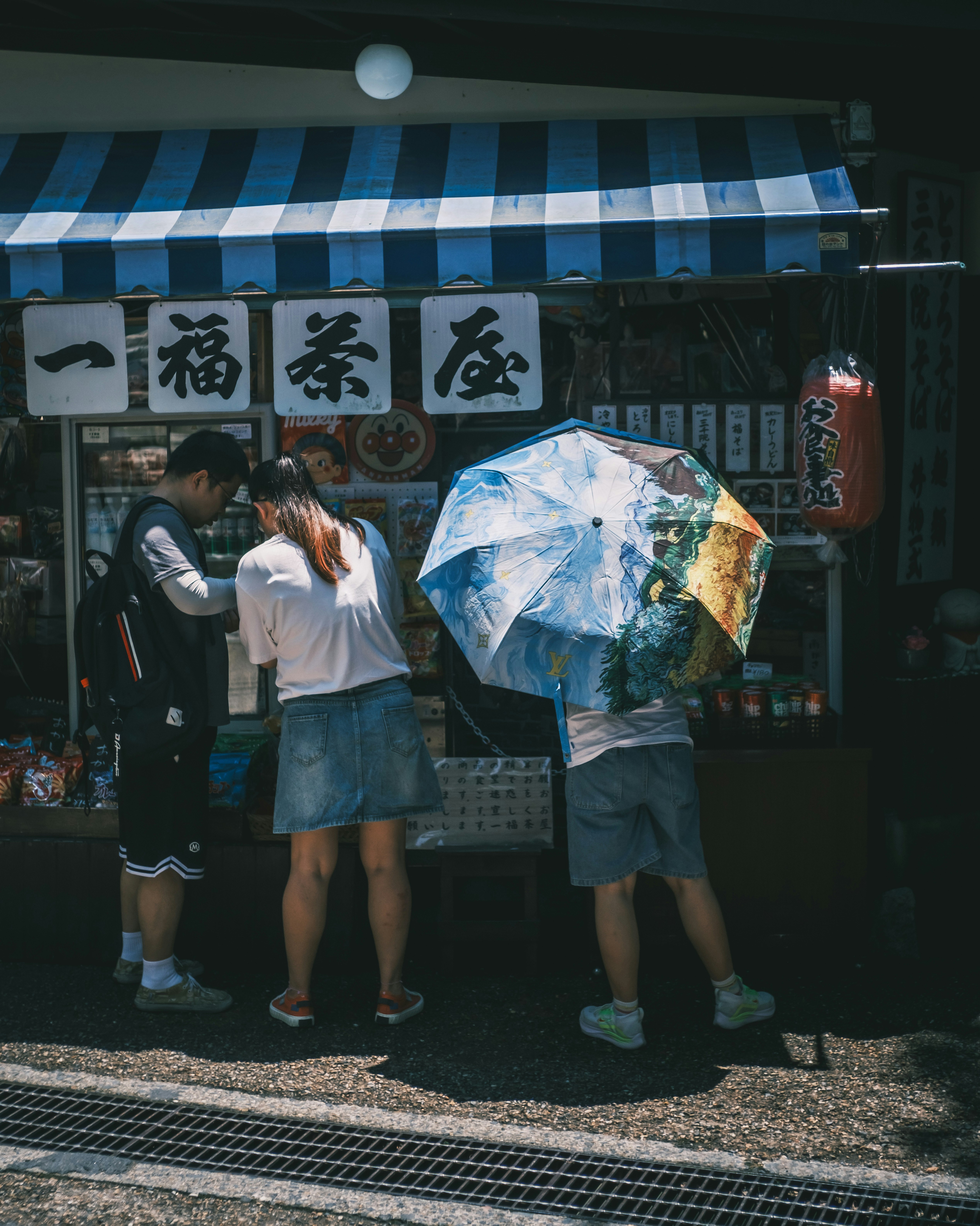 晴天の商店街で傘を持つ人々の軒先