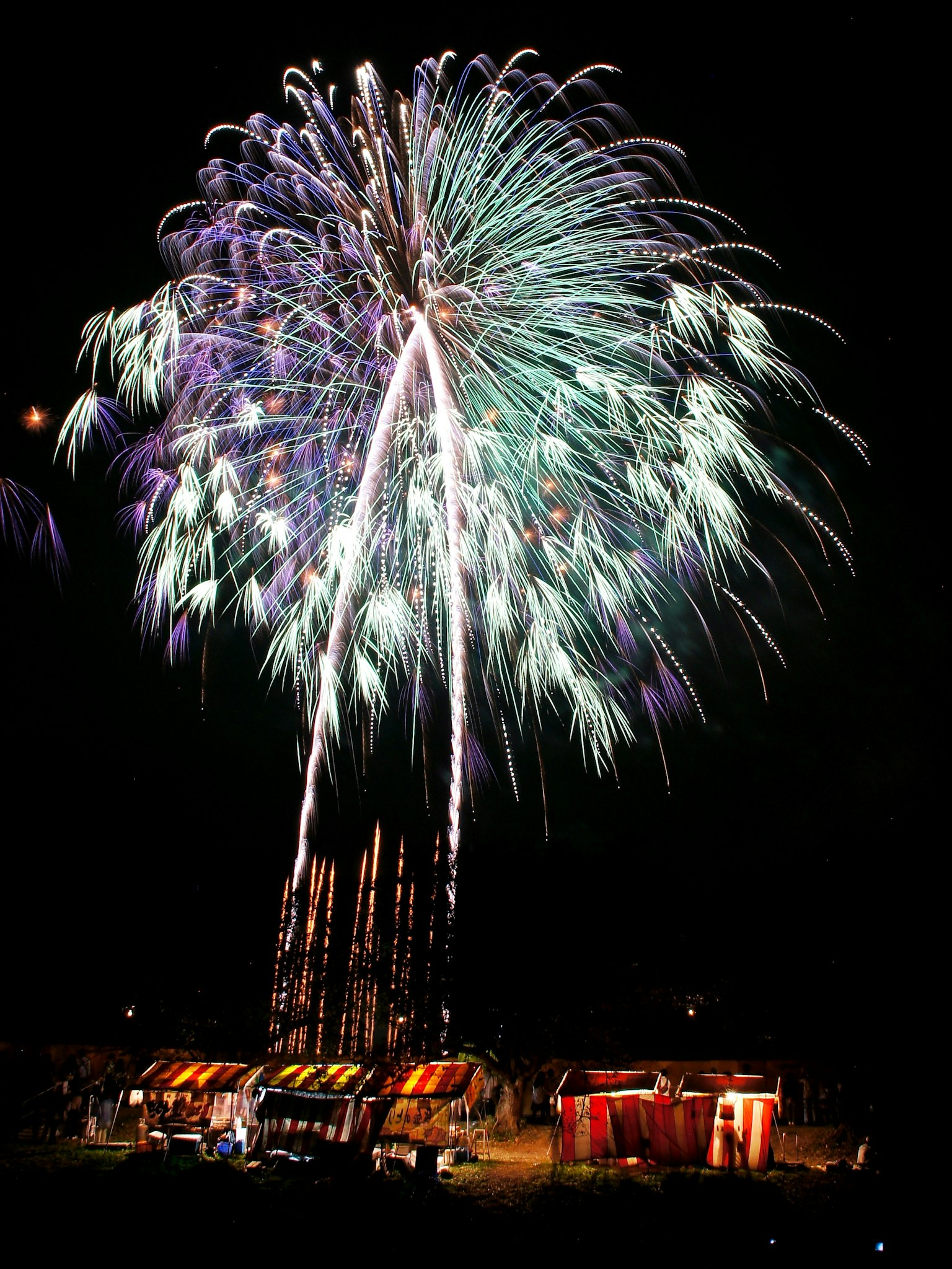 Feux d'artifice colorés éclatant dans le ciel nocturne au-dessus des tentes
