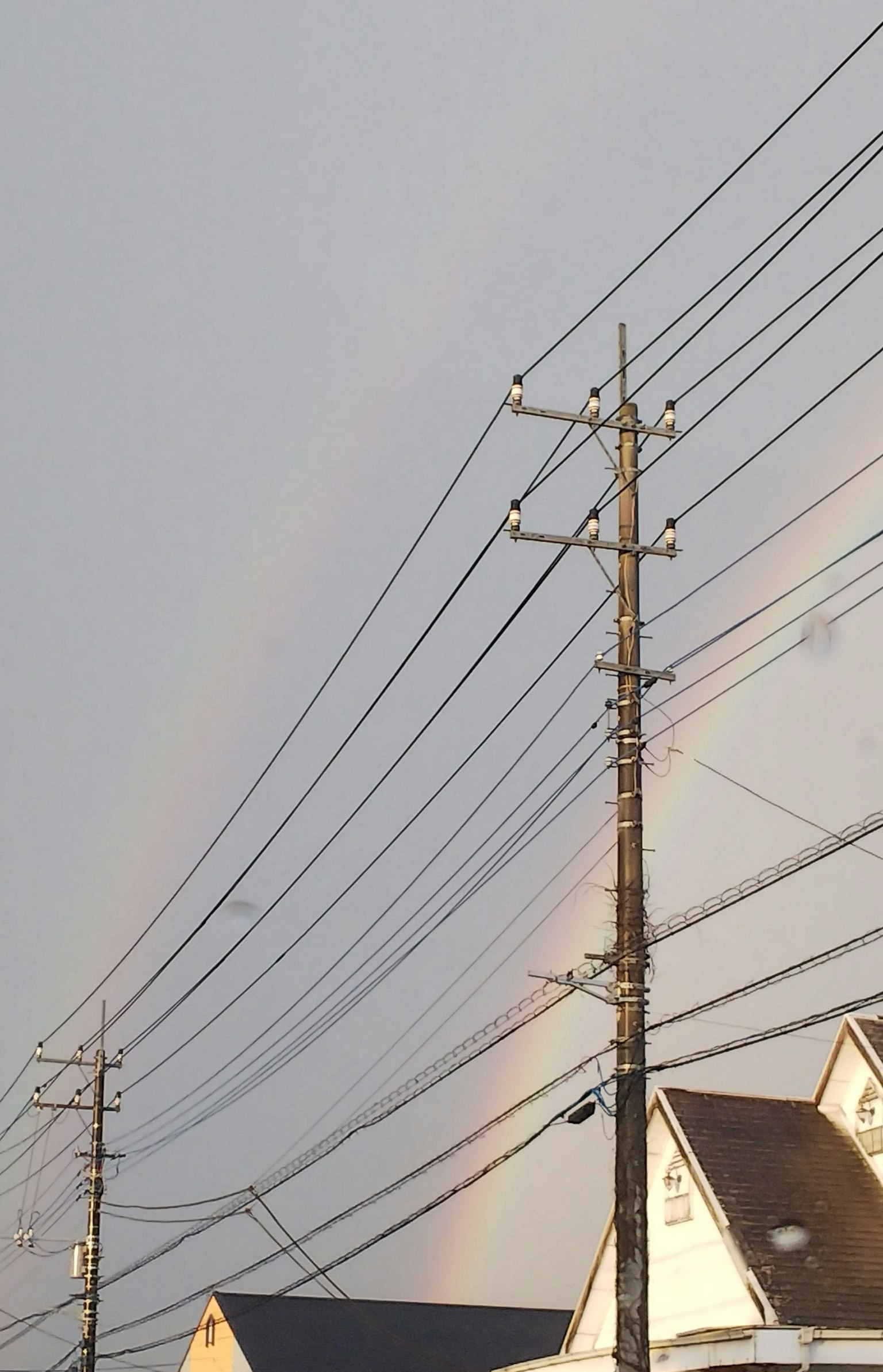 Una vista di un arcobaleno nel cielo con pali elettrici e cavi
