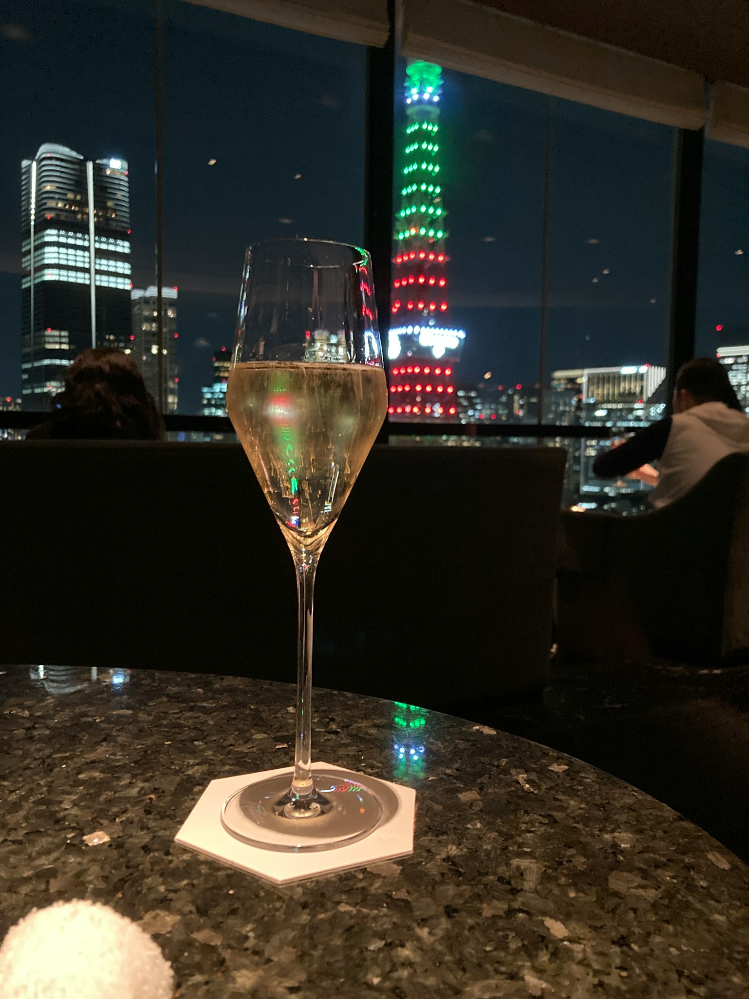 Gelas sampanye dengan Menara Tokyo yang diterangi di malam hari