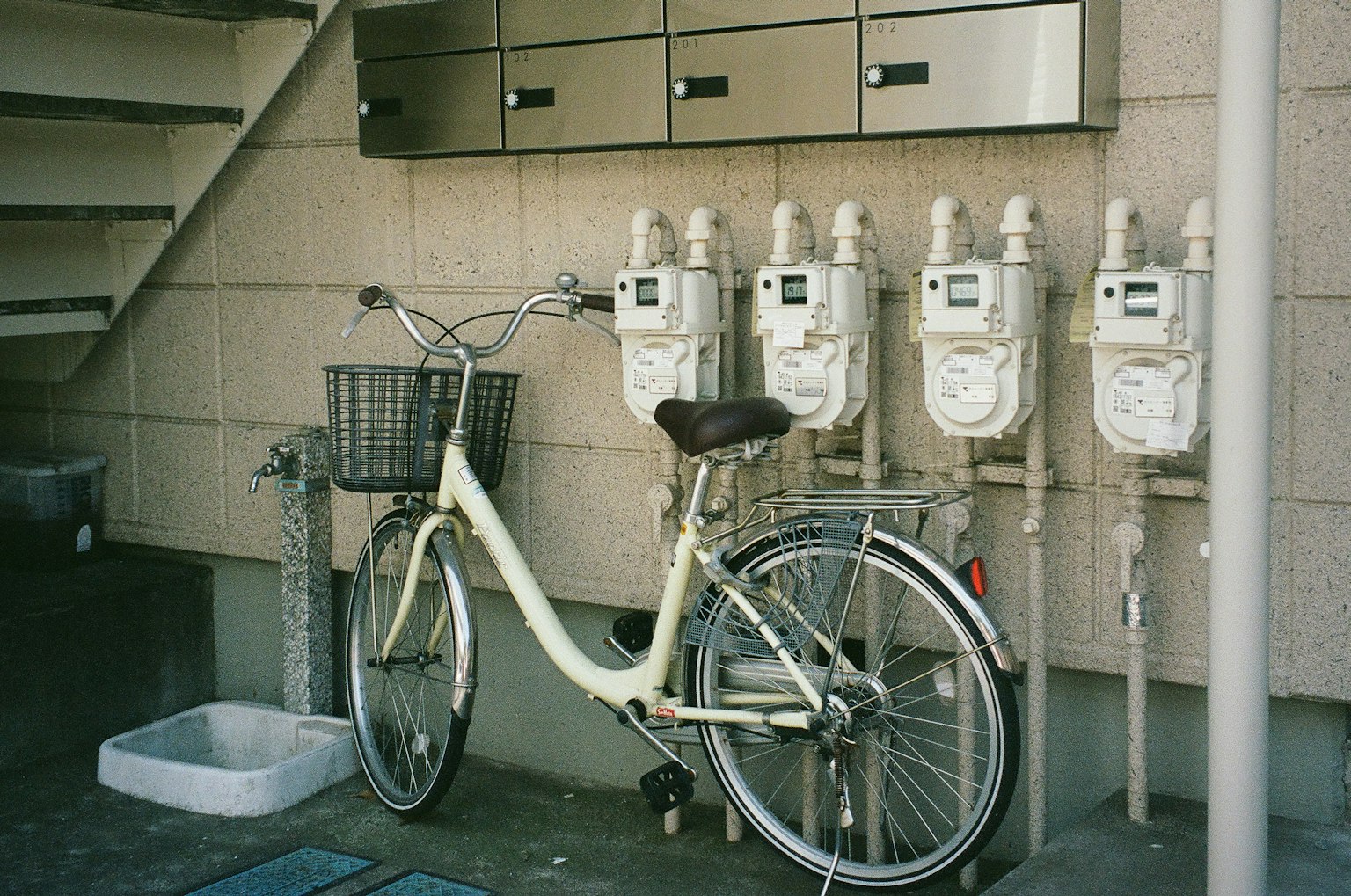 A white bicycle next to gas meters on a wall