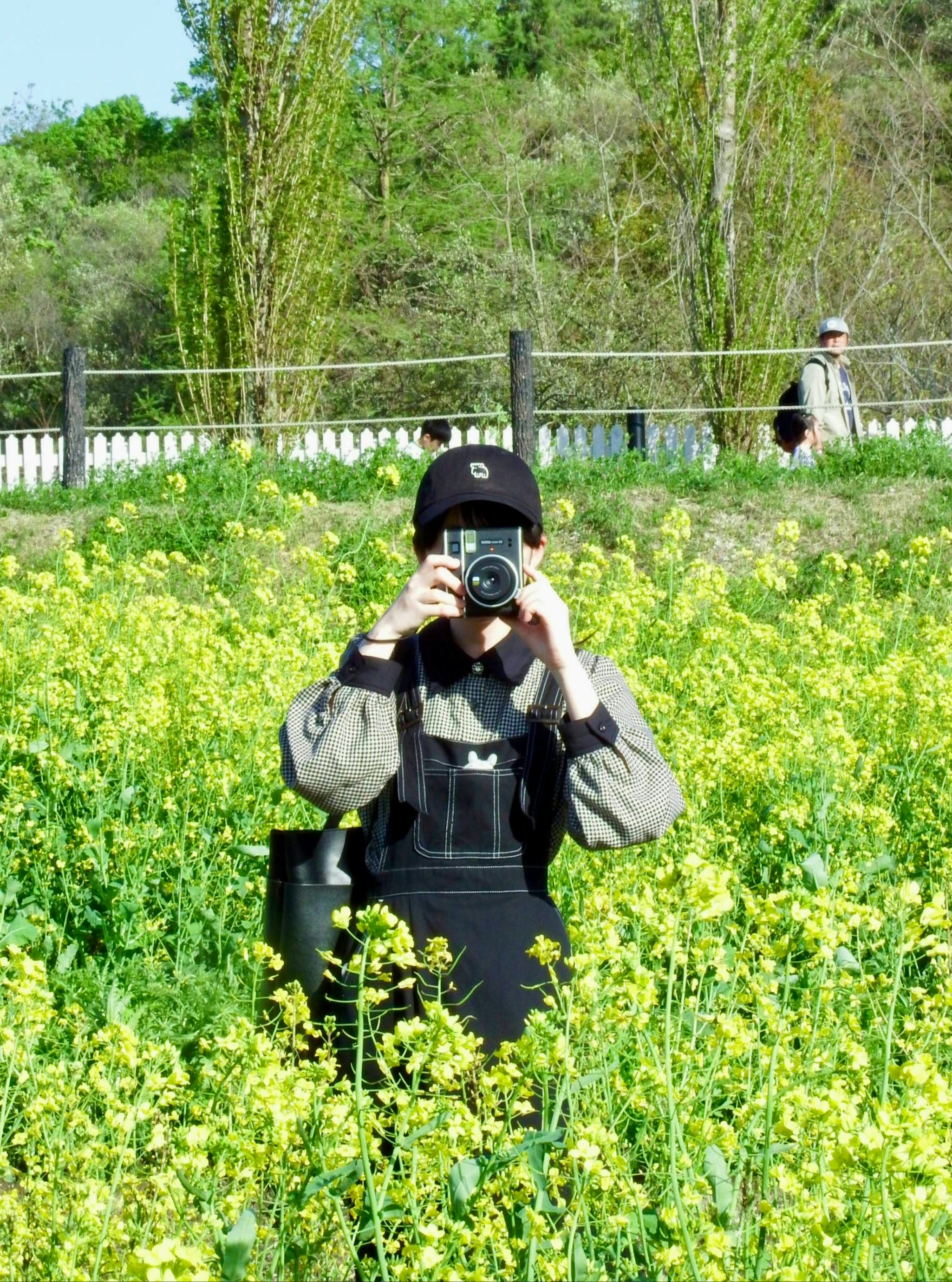 菜の花畑でカメラを構える友人