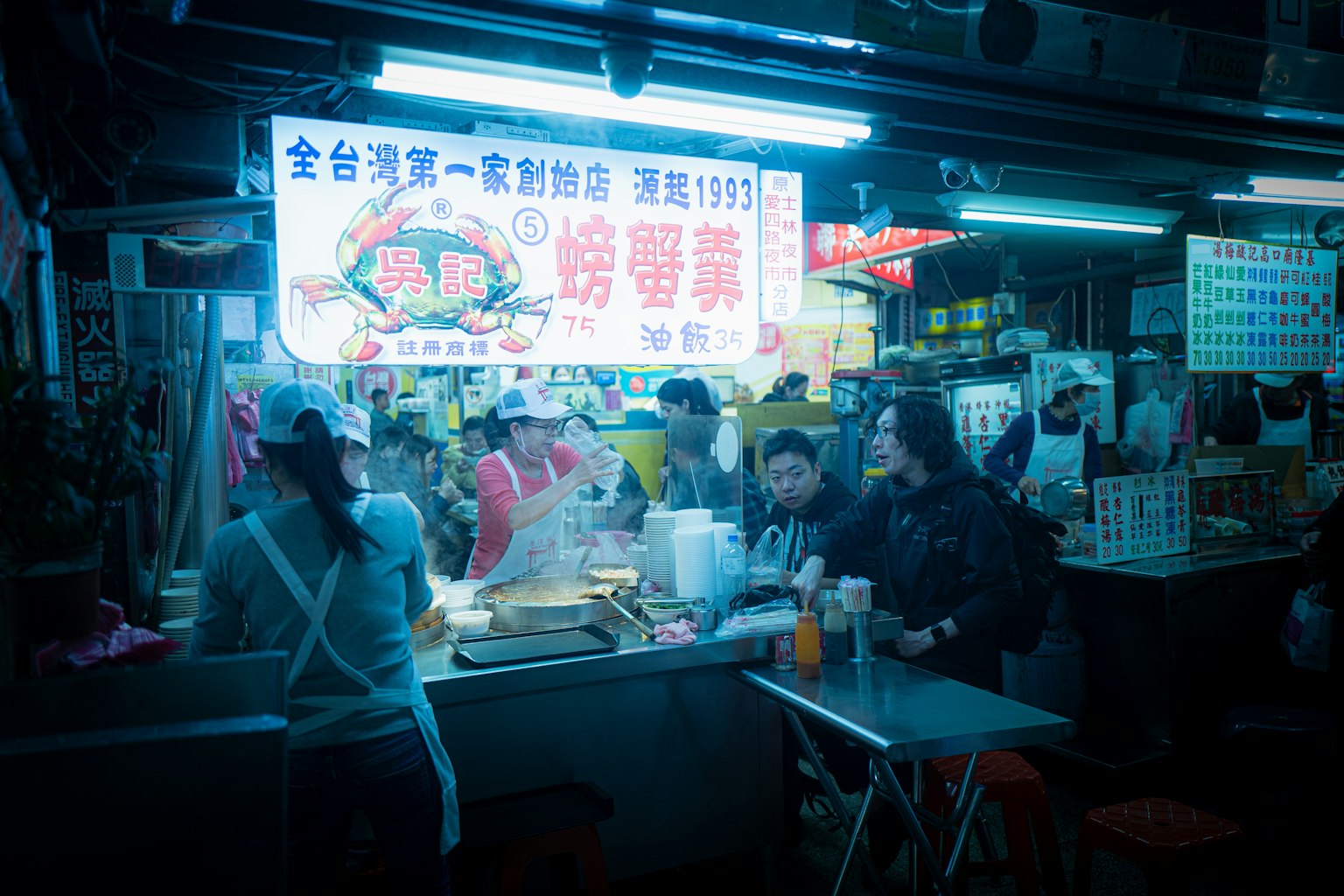 繁忙的夜市摊位，有工作人员和顾客