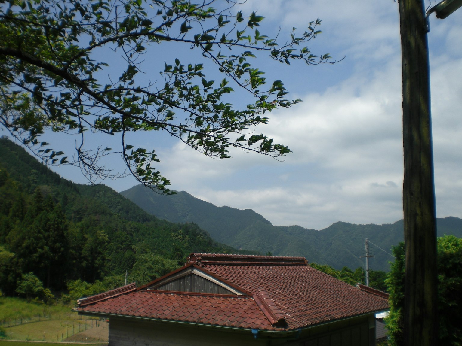 A red-roofed house surrounded by mountains and a blue sky