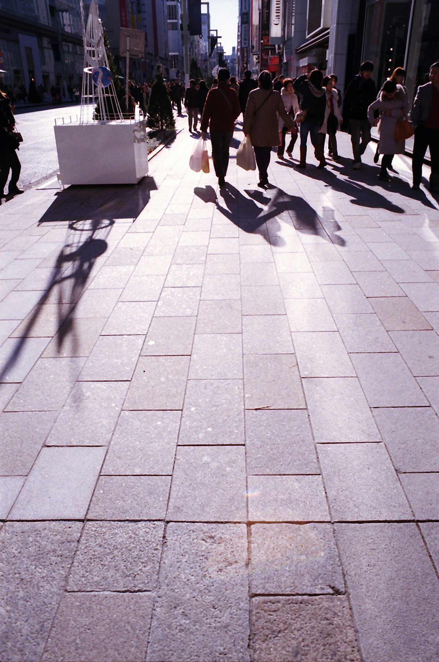 Städtische Szene mit Menschen, die gehen und Schatten