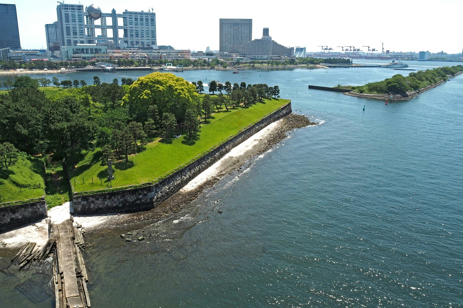 Malerei eines üppigen Parks am Wasser mit städtischen Gebäuden im Hintergrund