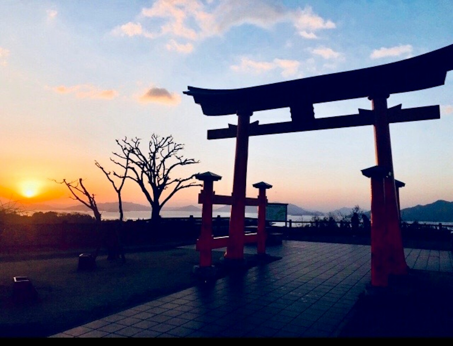 红色鸟居在日落和树木的剪影中