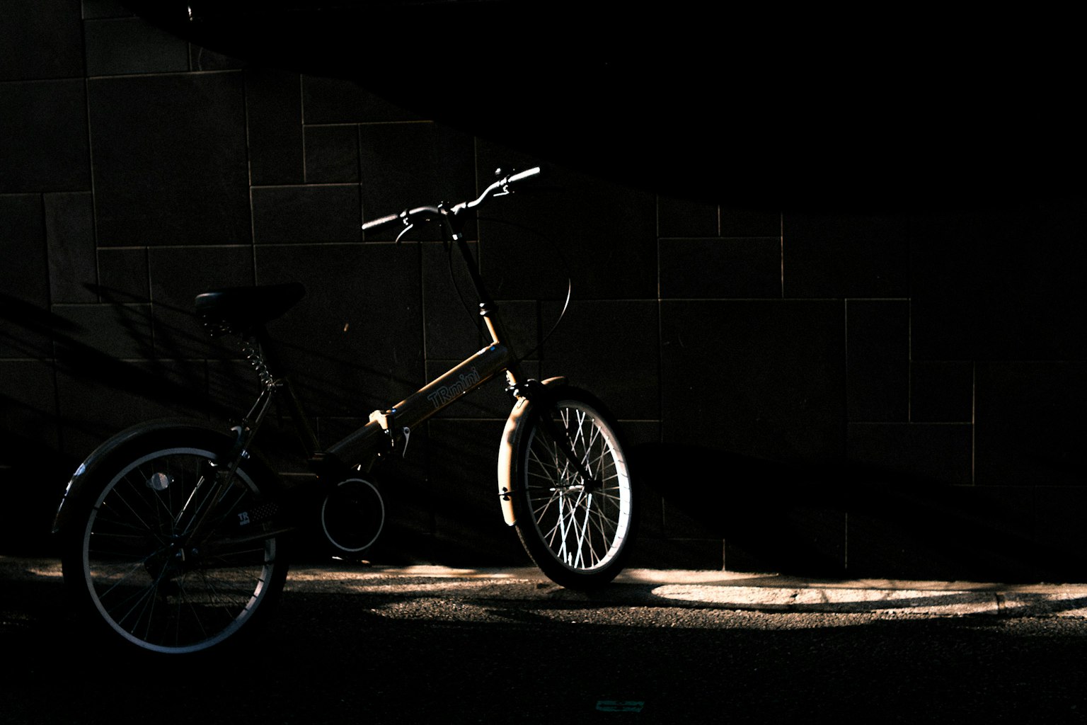 A bicycle illuminated by light against a dark background
