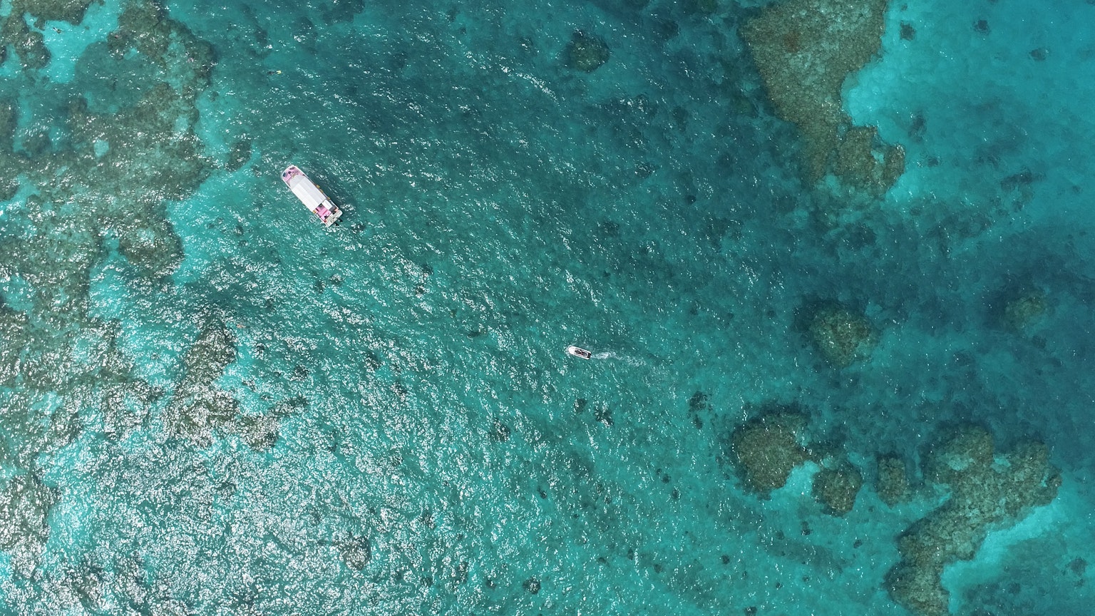 一艘漂浮在藍色海洋上的船和珊瑚礁