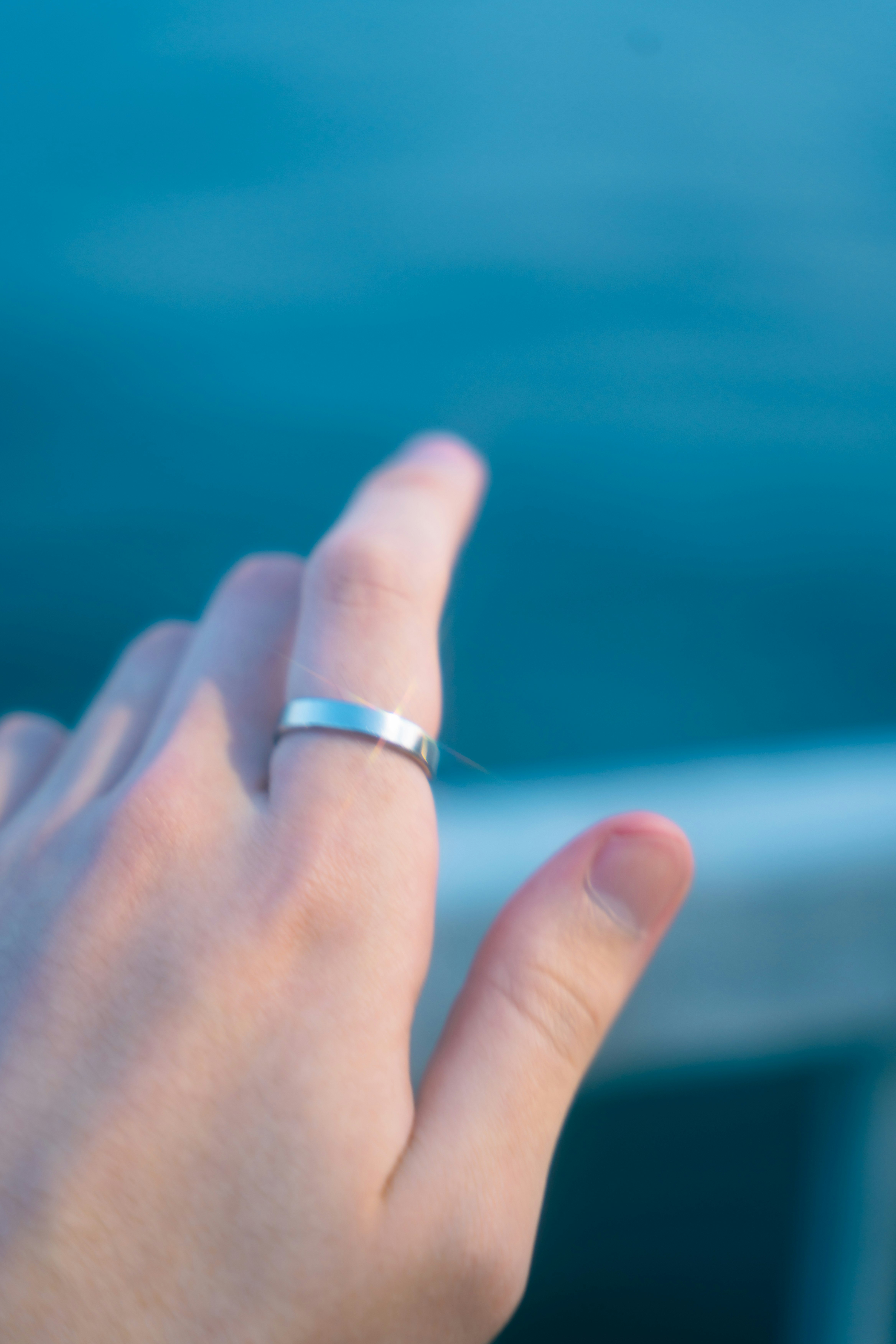 mains en train d’enfiler une bague sur fond bleu