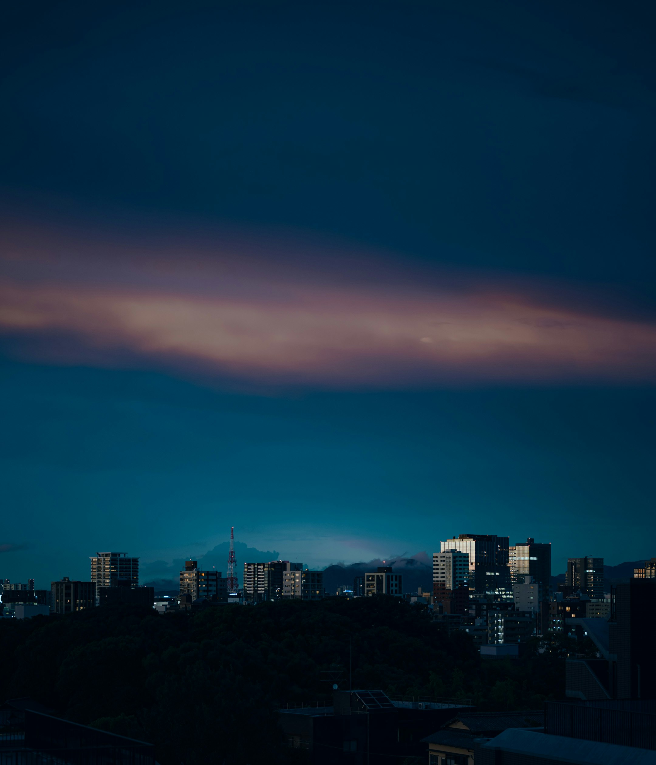夜の街並みを覆う青い空と薄い雲のグラデーション