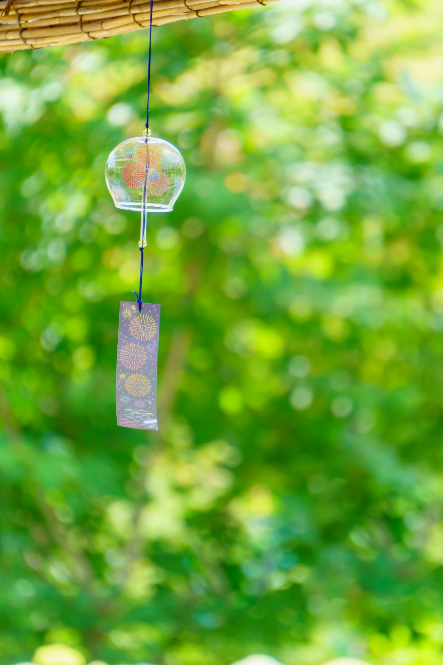 Eine transparente Windglocke schwingt vor einem grünen Hintergrund