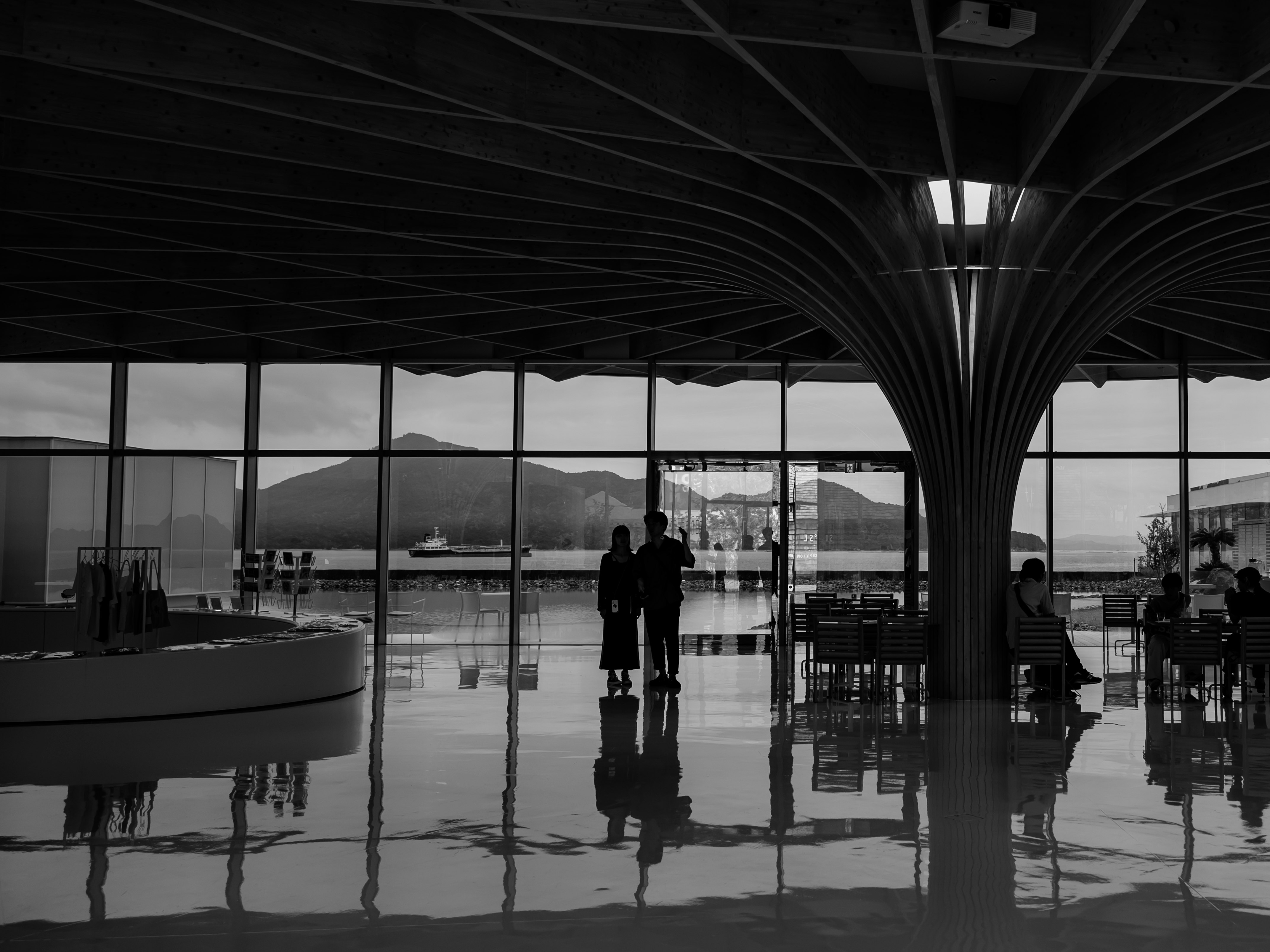Silhouetted people reflected in a glass-walled corridor