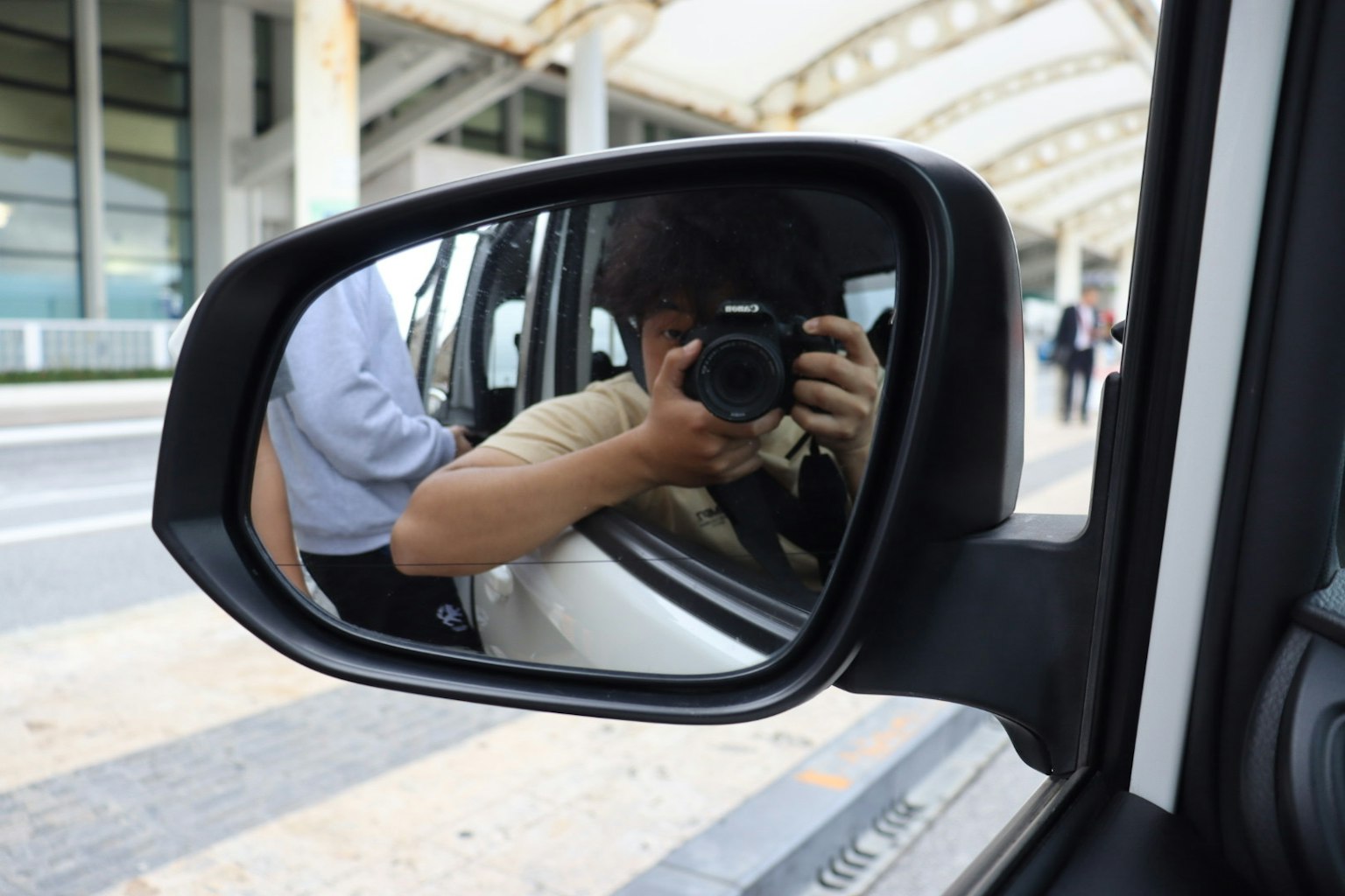 Person mit Kamera, die im Seitenspiegel eines Autos reflektiert wird