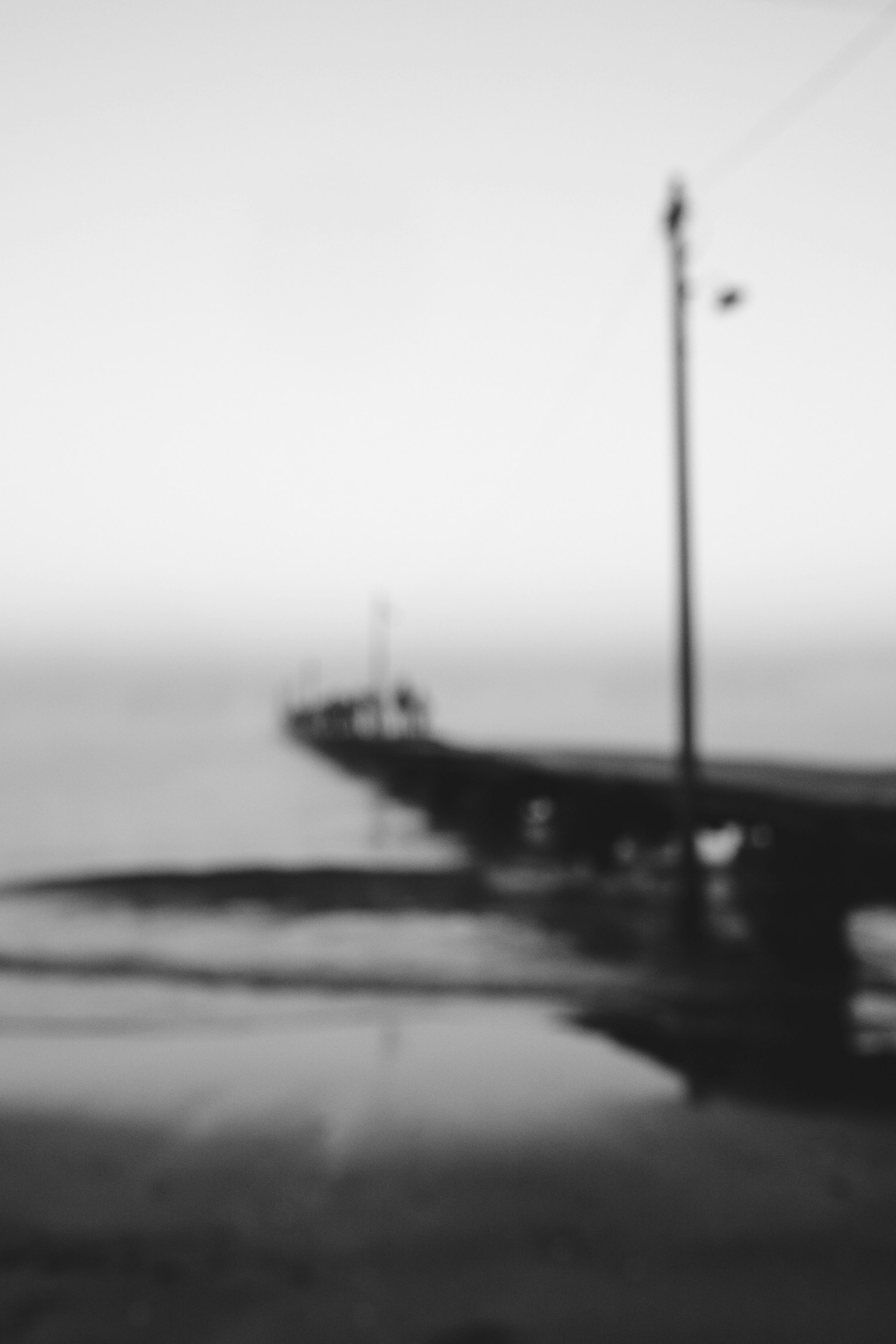 Image floue en noir et blanc d'un quai s'étendant dans la mer