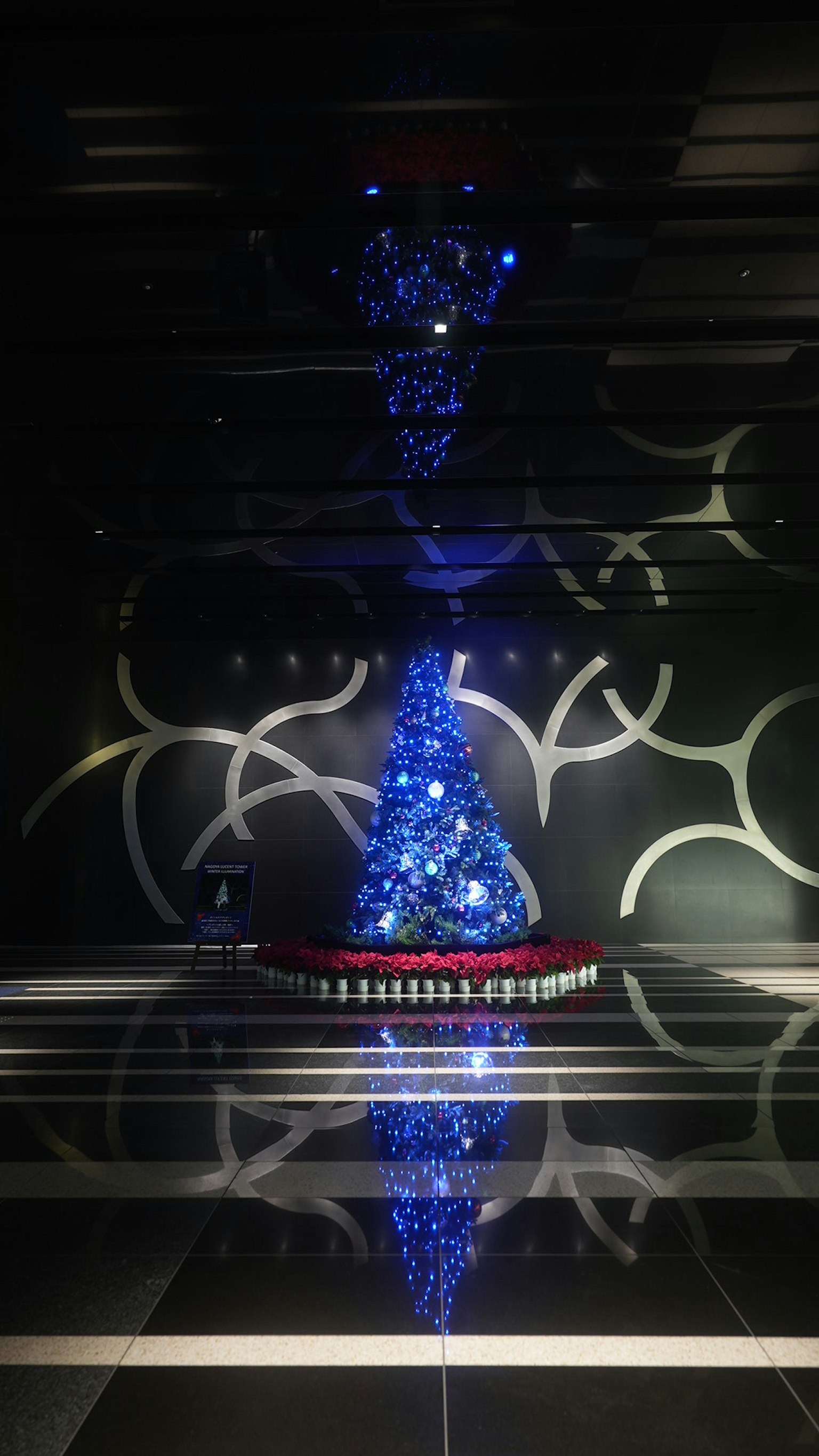 Albero di Natale unico decorato con luci blu che si riflette in un interno moderno