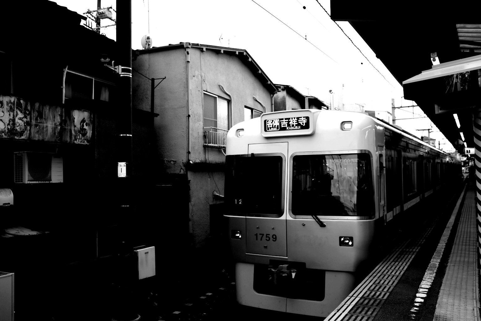 Image en noir et blanc d'un train à une station avec un vieux bâtiment