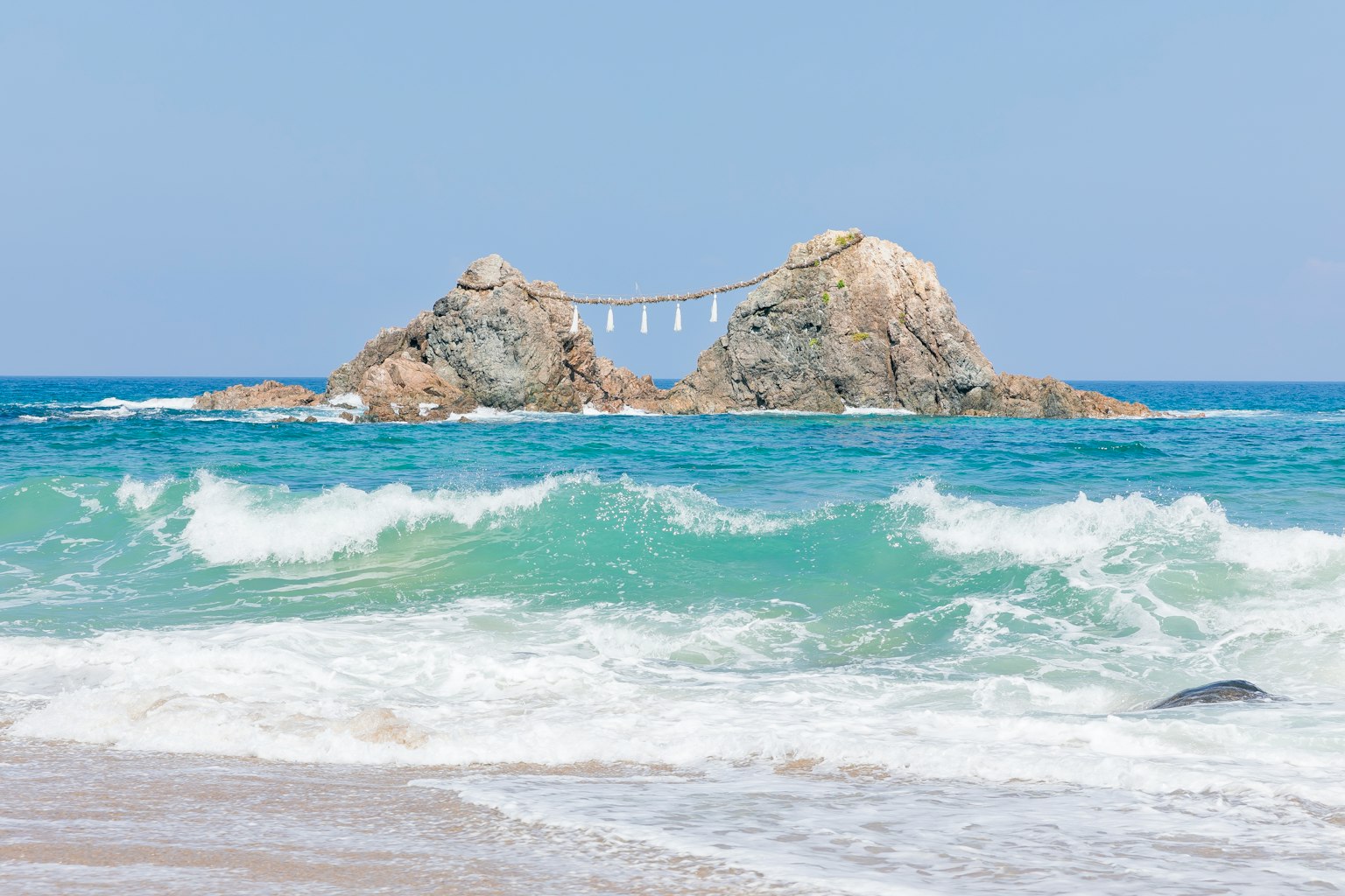 Vue panoramique de vagues océaniques bleues s'écrasant sur des rochers avec un pont reliant deux rochers