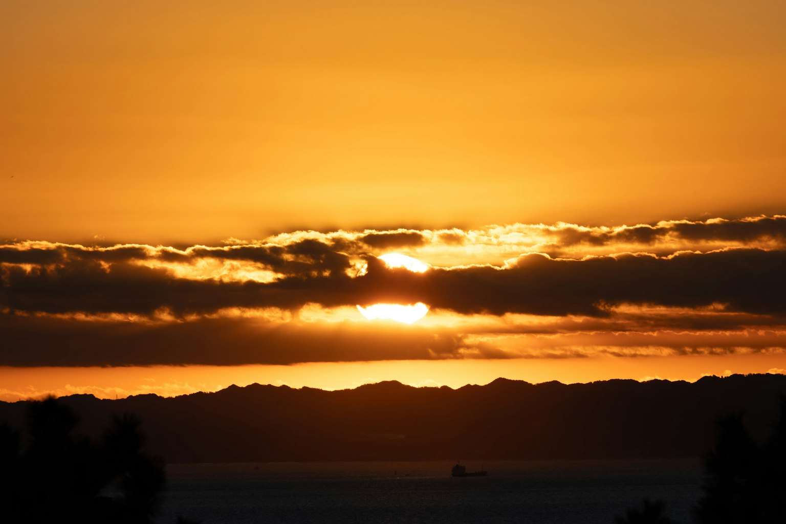 Magnifique coucher de soleil orange émergeant des nuages au-dessus des montagnes
