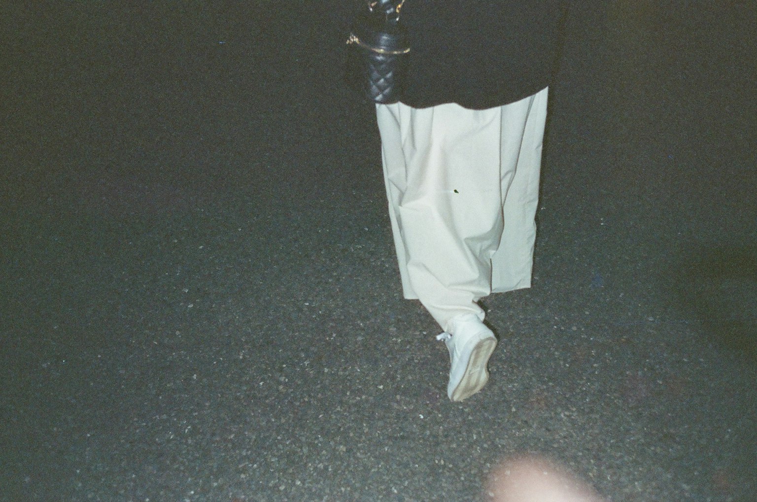 Piedi in pantaloni bianchi su una superficie scura di notte
