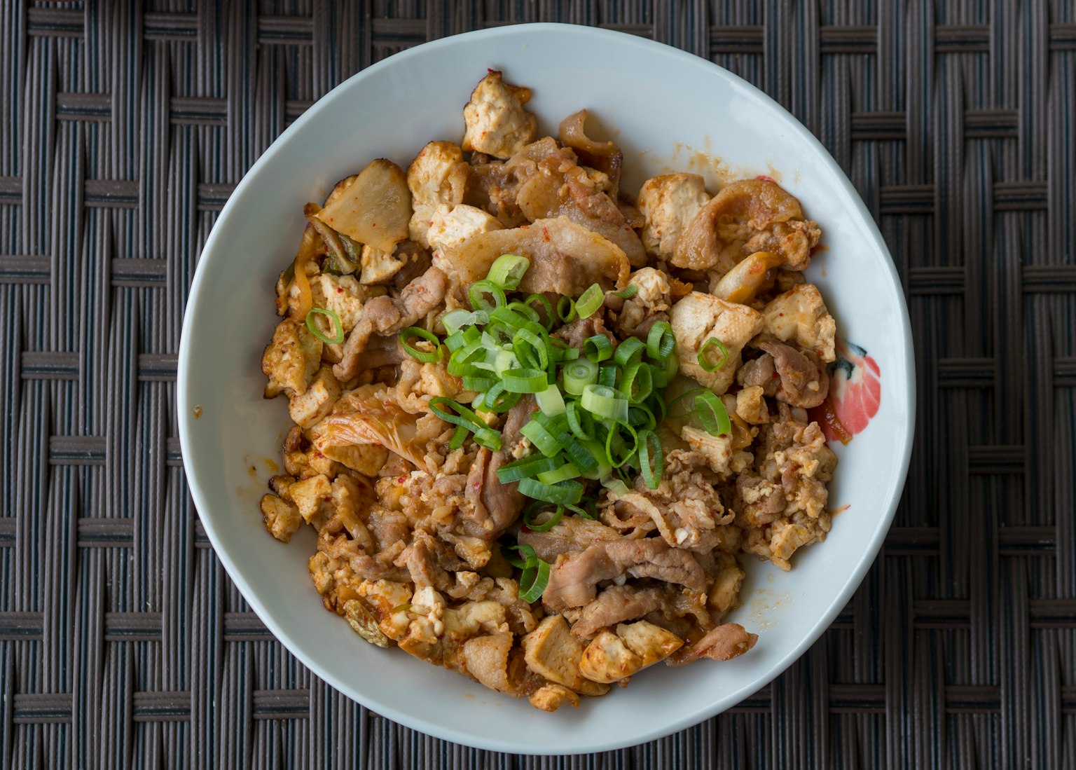 Un tazón de arroz con pollo y huevo sabroso cubierto con cebollitas verdes
