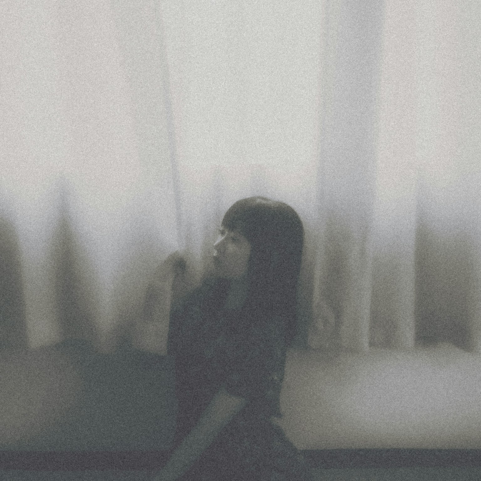 Silhouette of a woman sitting in front of curtains