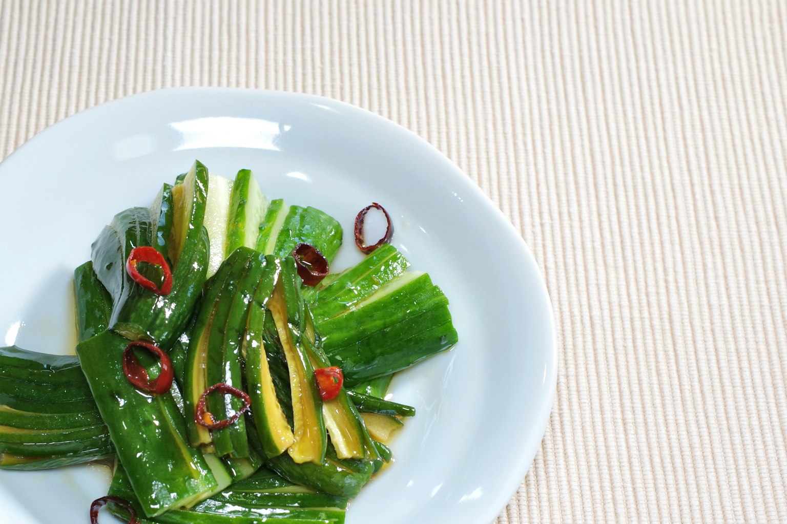 绿色蔬菜沙拉上有红辣椒配料的白盘子