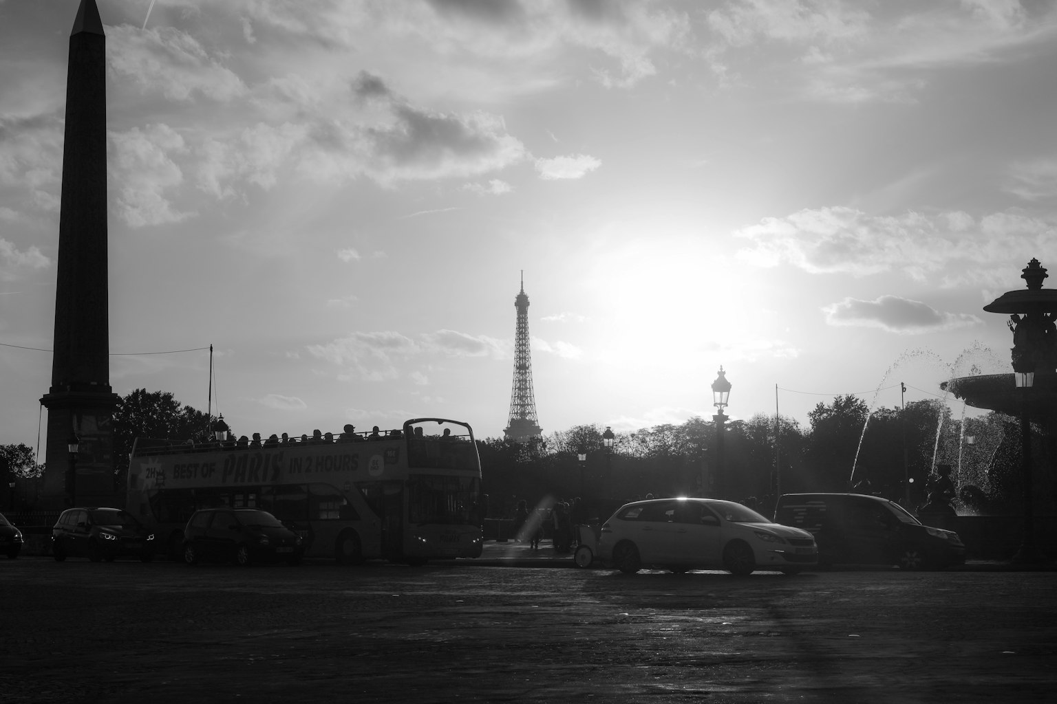 Siluet Menara Eiffel dan obelisk melawan matahari terbenam dalam hitam putih